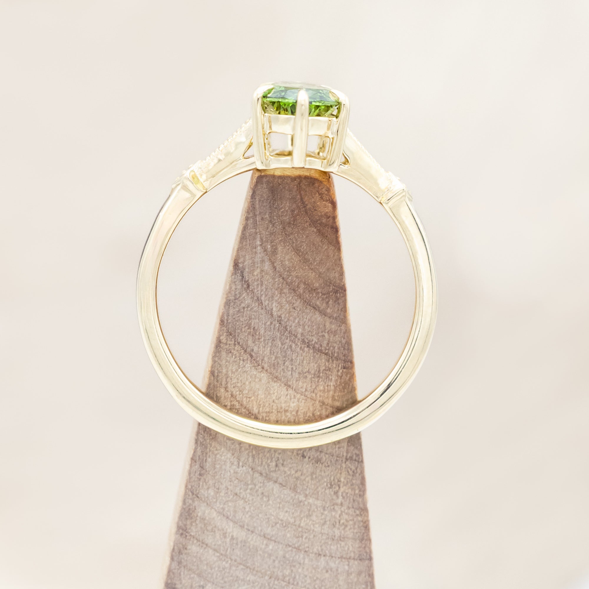 14K yellow gold ring with a green diamond on a neutral background