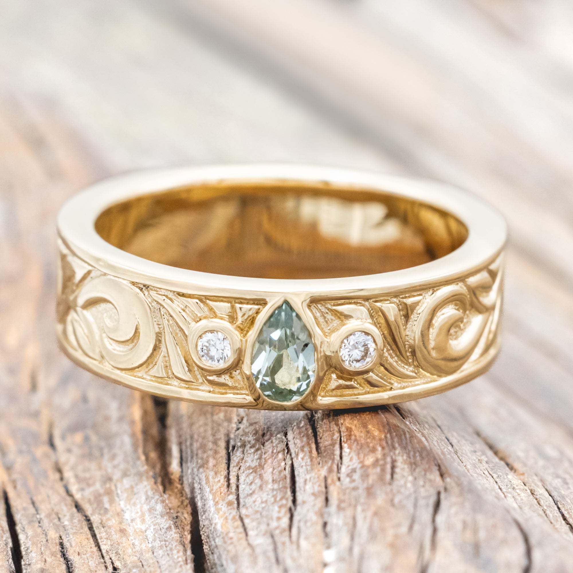 Yellow gold ring with lab sapphire and diamond accent on a wooden surface
