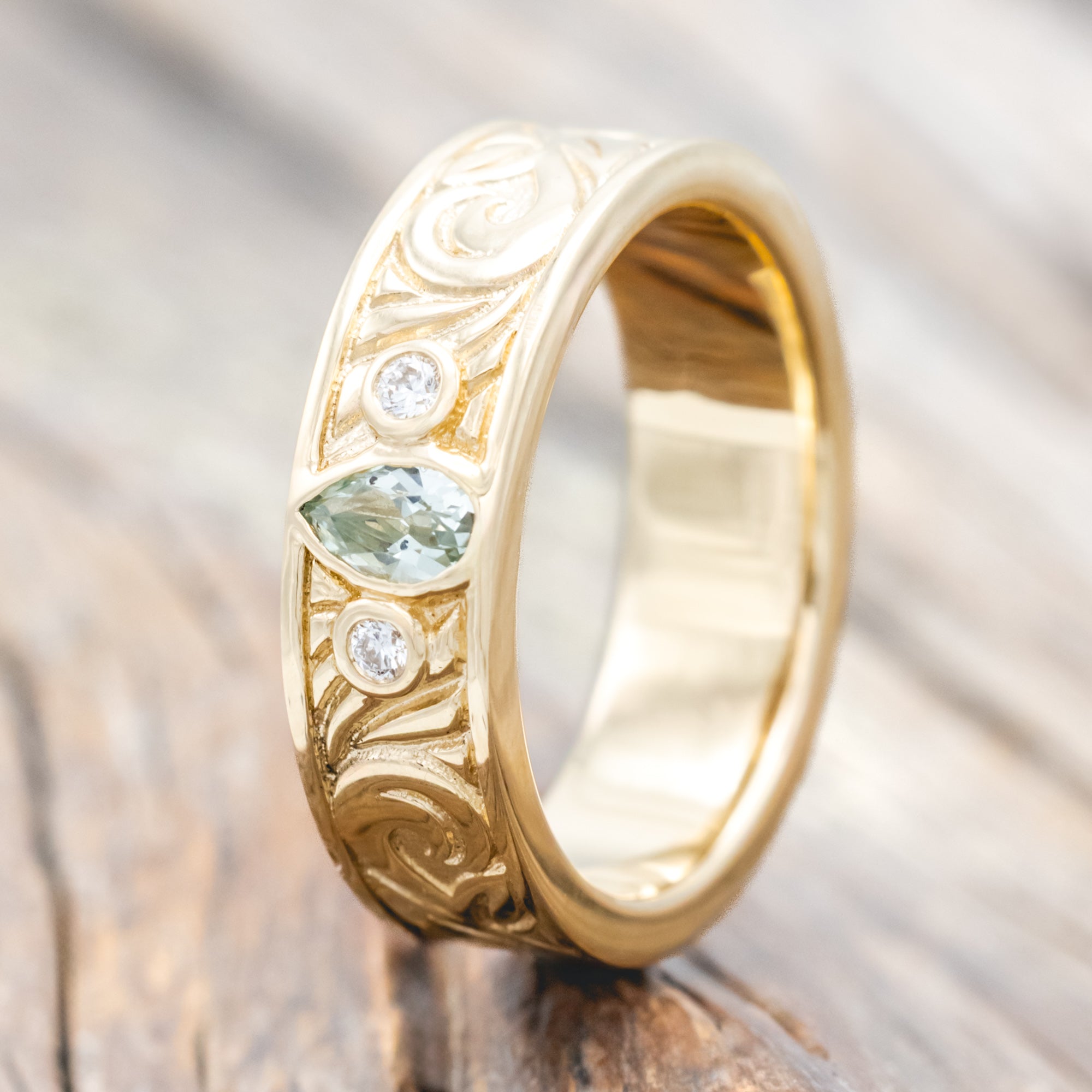 Yellow gold ring with lab sapphire and diamond accent on a wooden surface