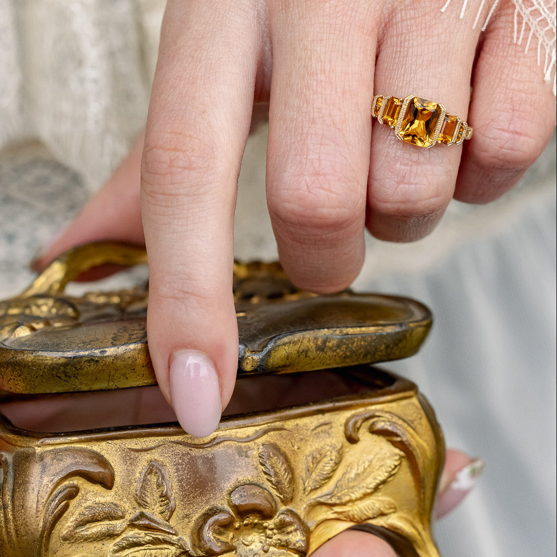 On hand photo of "Hazel" - accented-style citrine women's engagement ring with citrine accents on a 14K gold miligrain band