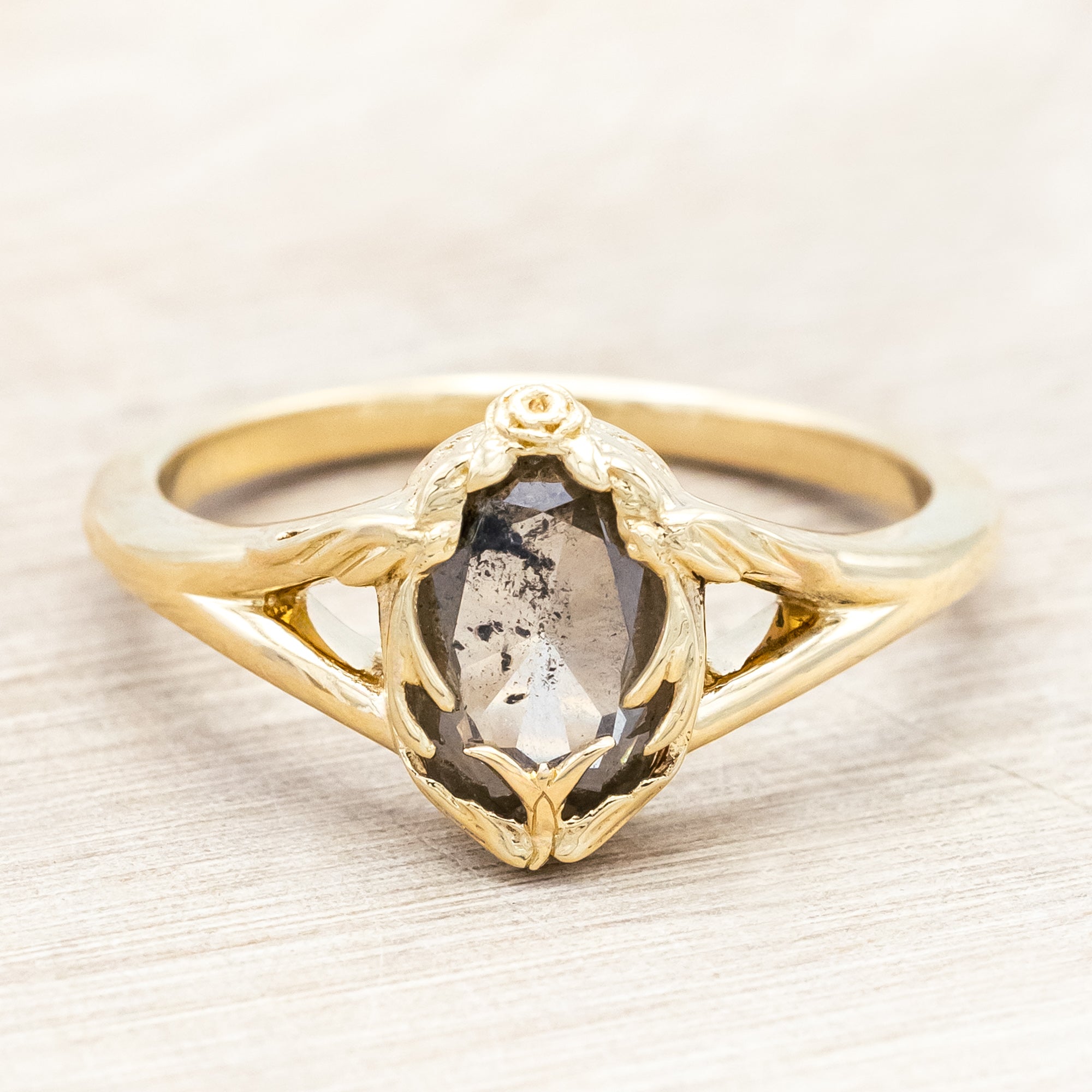 Gold ring with salt & pepper diamond with swallow filigree against beige background