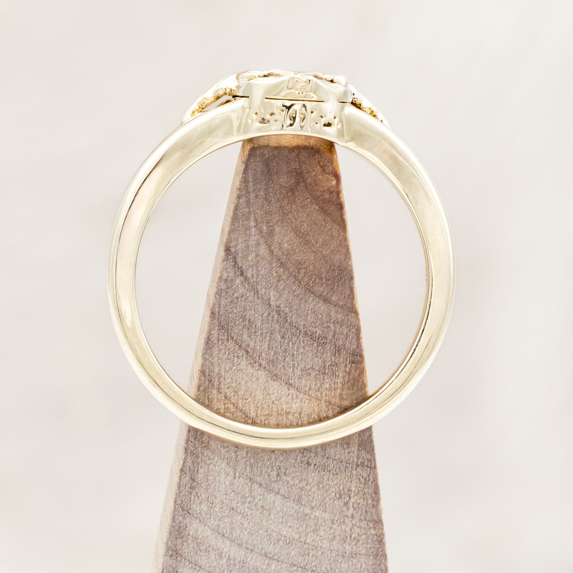 Gold ring with salt & pepper diamond with swallow filigree against beige background