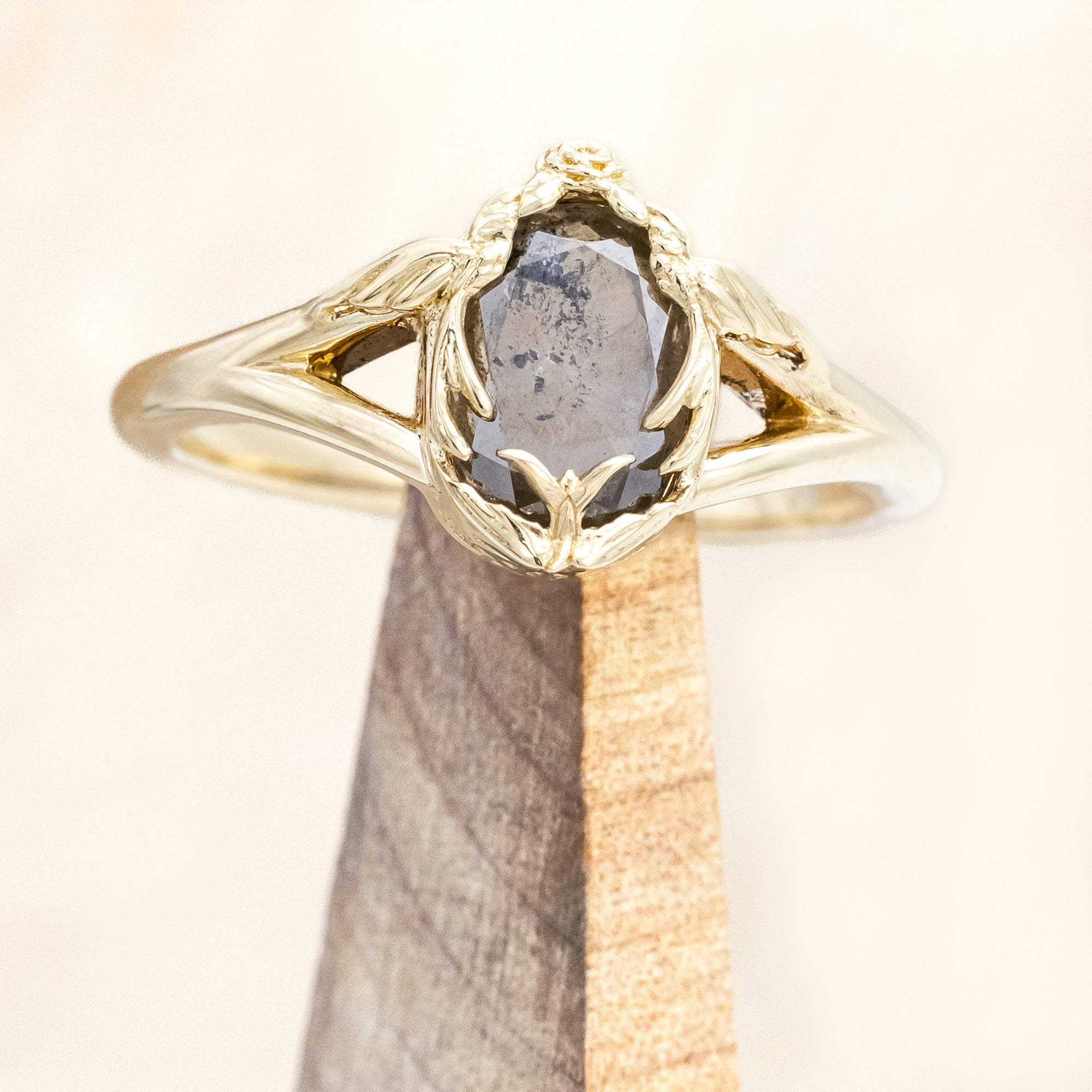 Gold ring with salt & pepper diamond with swallow filigree against beige background