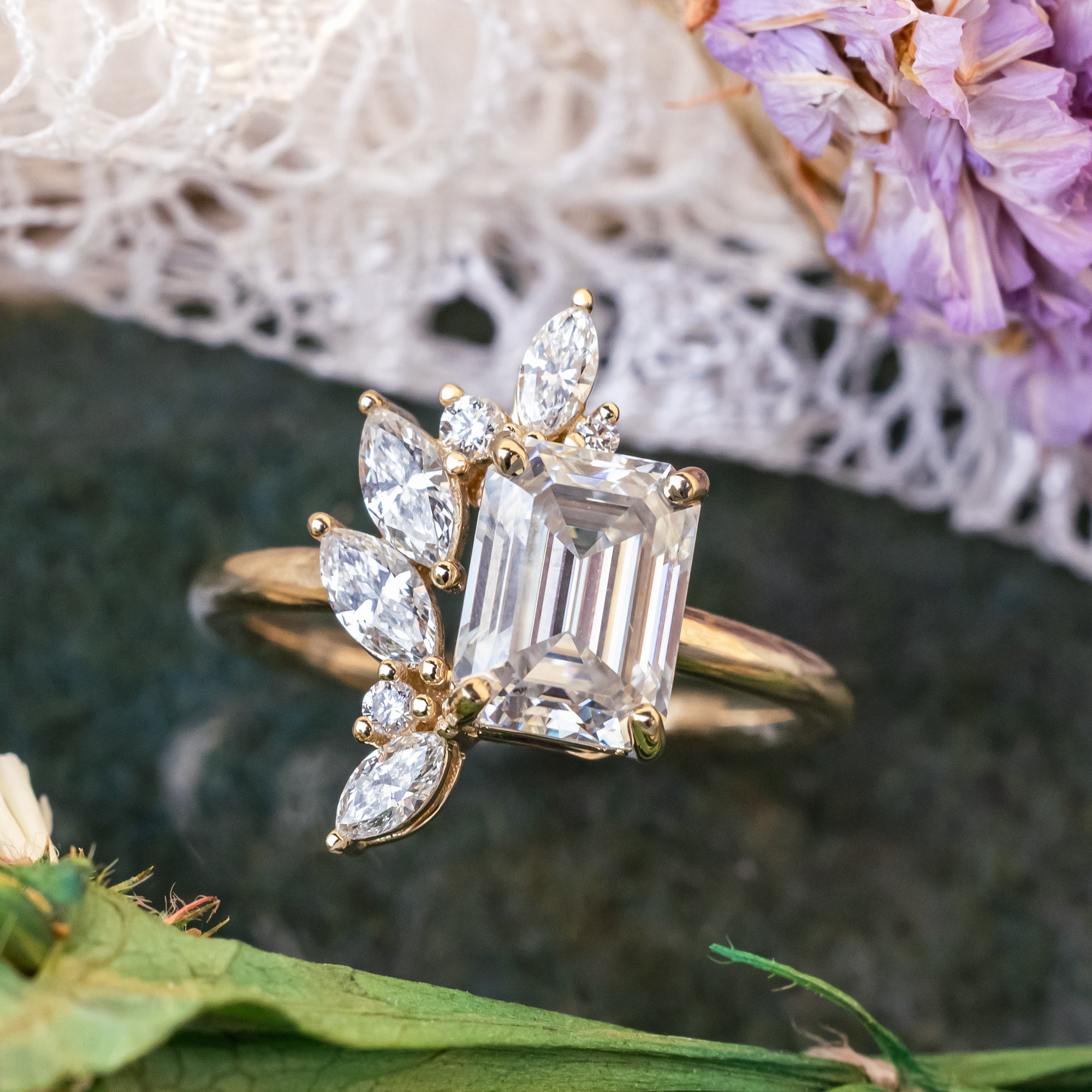 Gold ring with emerald-cut lab diamond and marquise diamond accents on a natural background