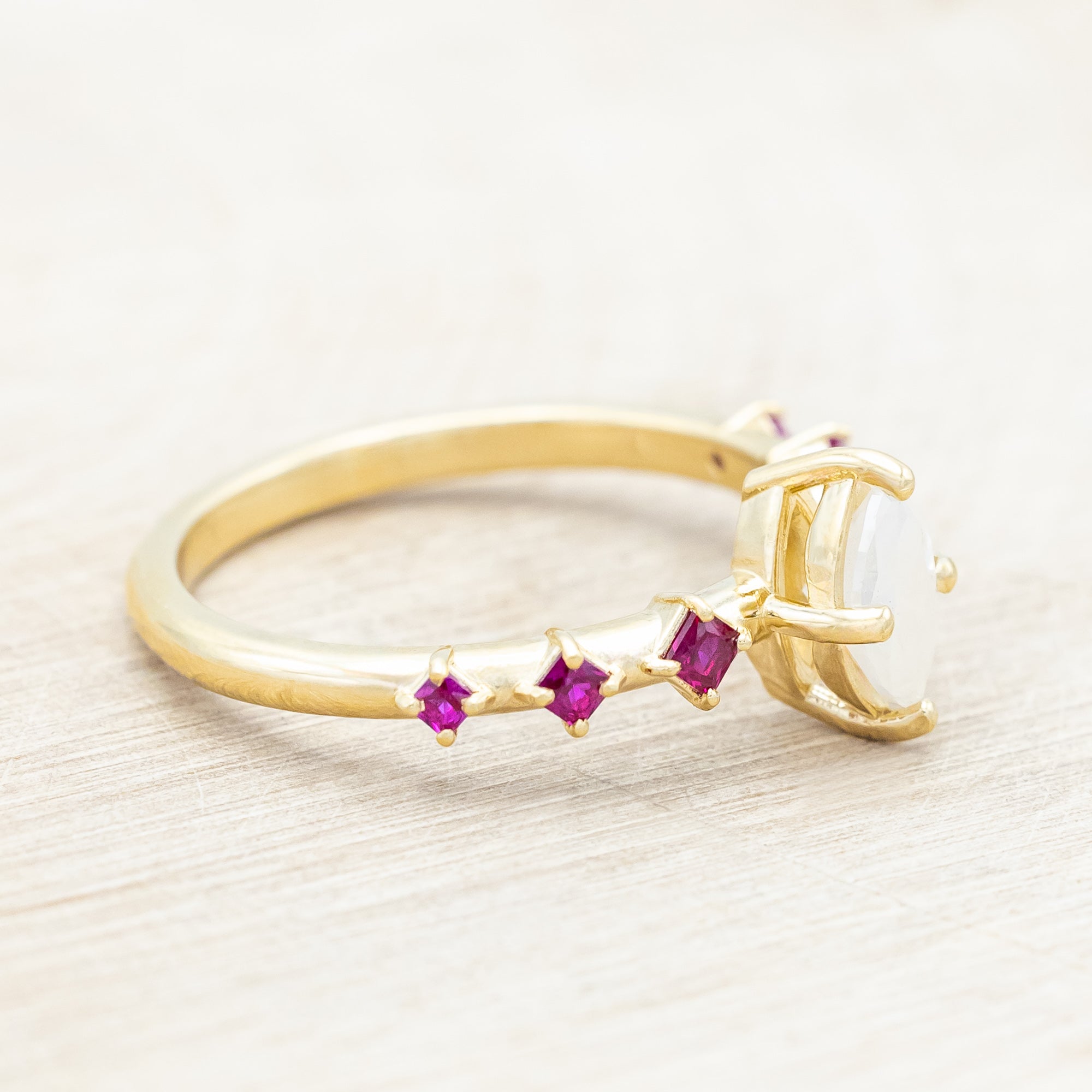 Gold ring with a central icy salt & pepper diamond with ruby accents on a beige background