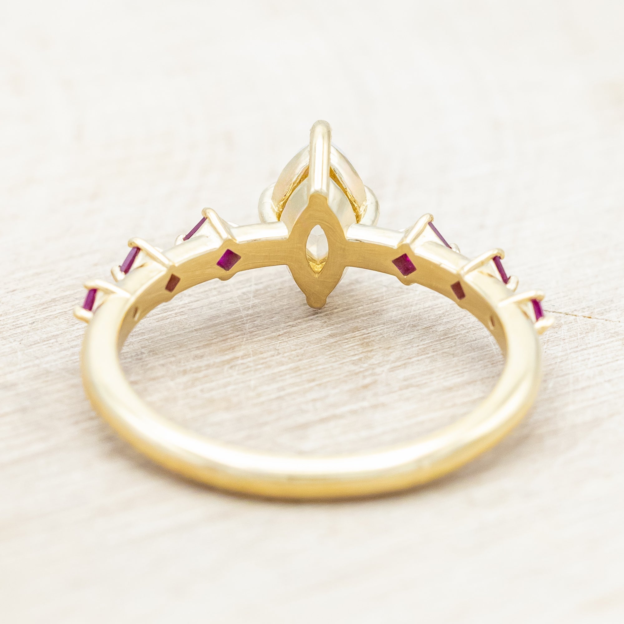 Gold ring with a central icy salt & pepper diamond with ruby accents on a beige background