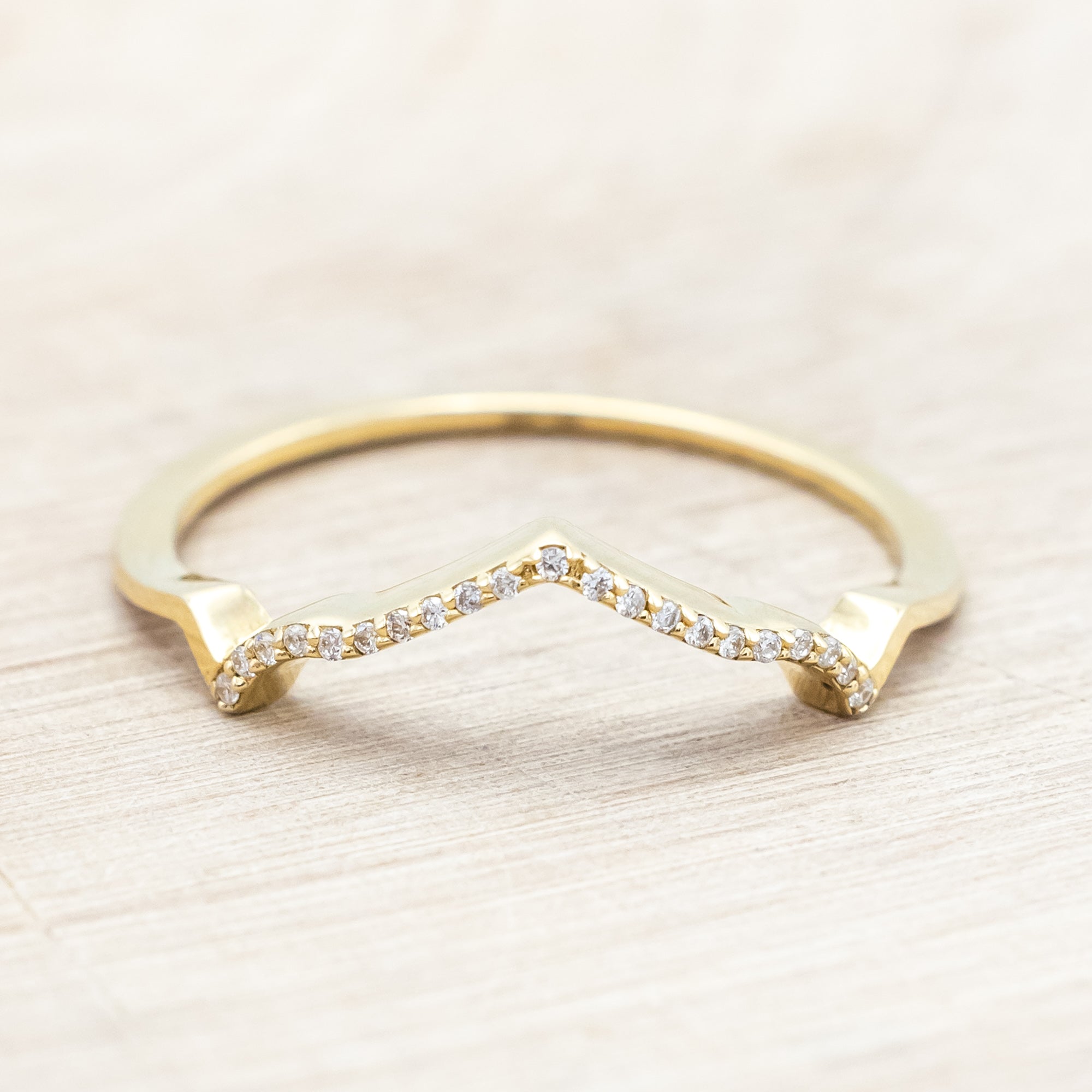 Yellow gold ring with diamond accents on a beige background