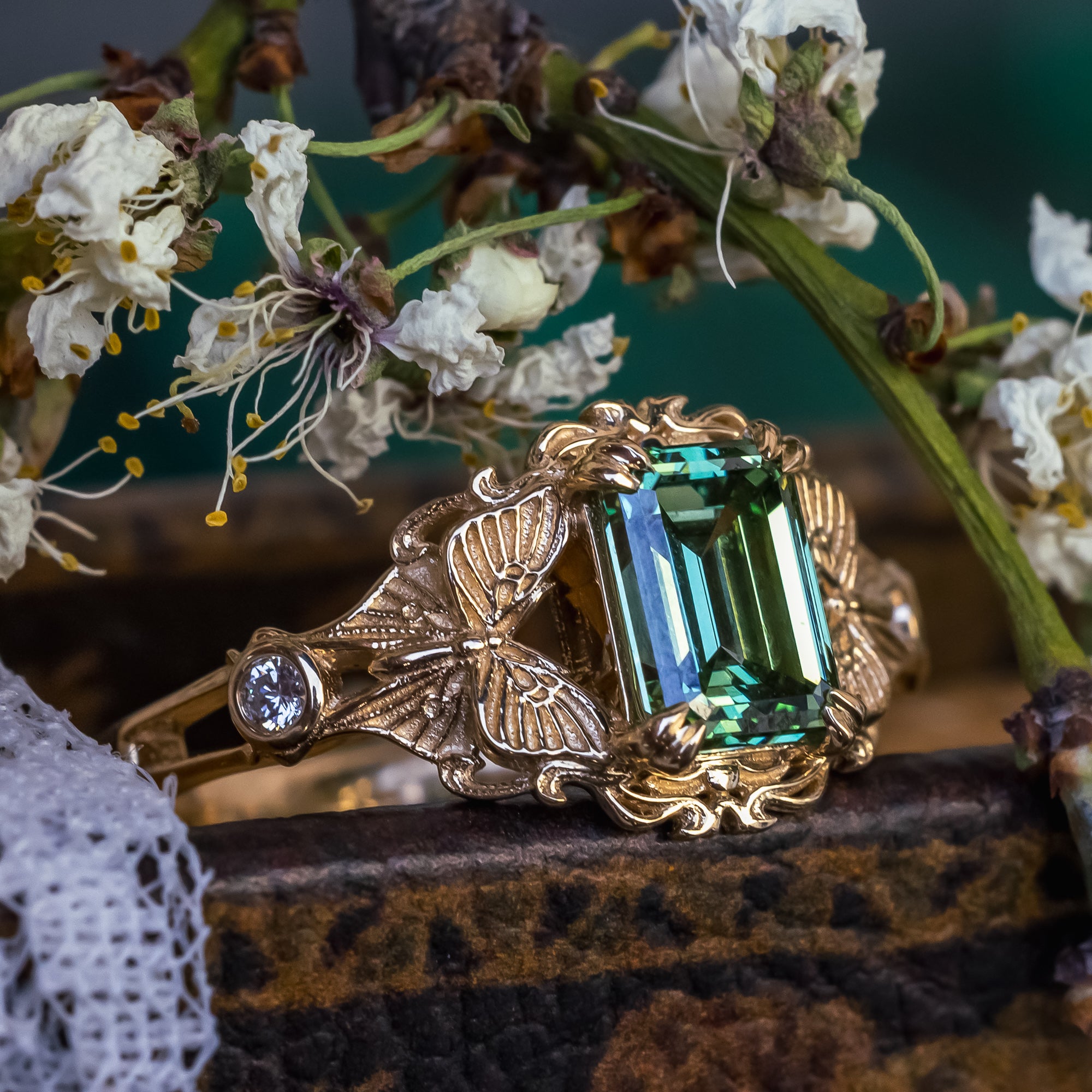 Gold ring with green lab diamond on a floral background