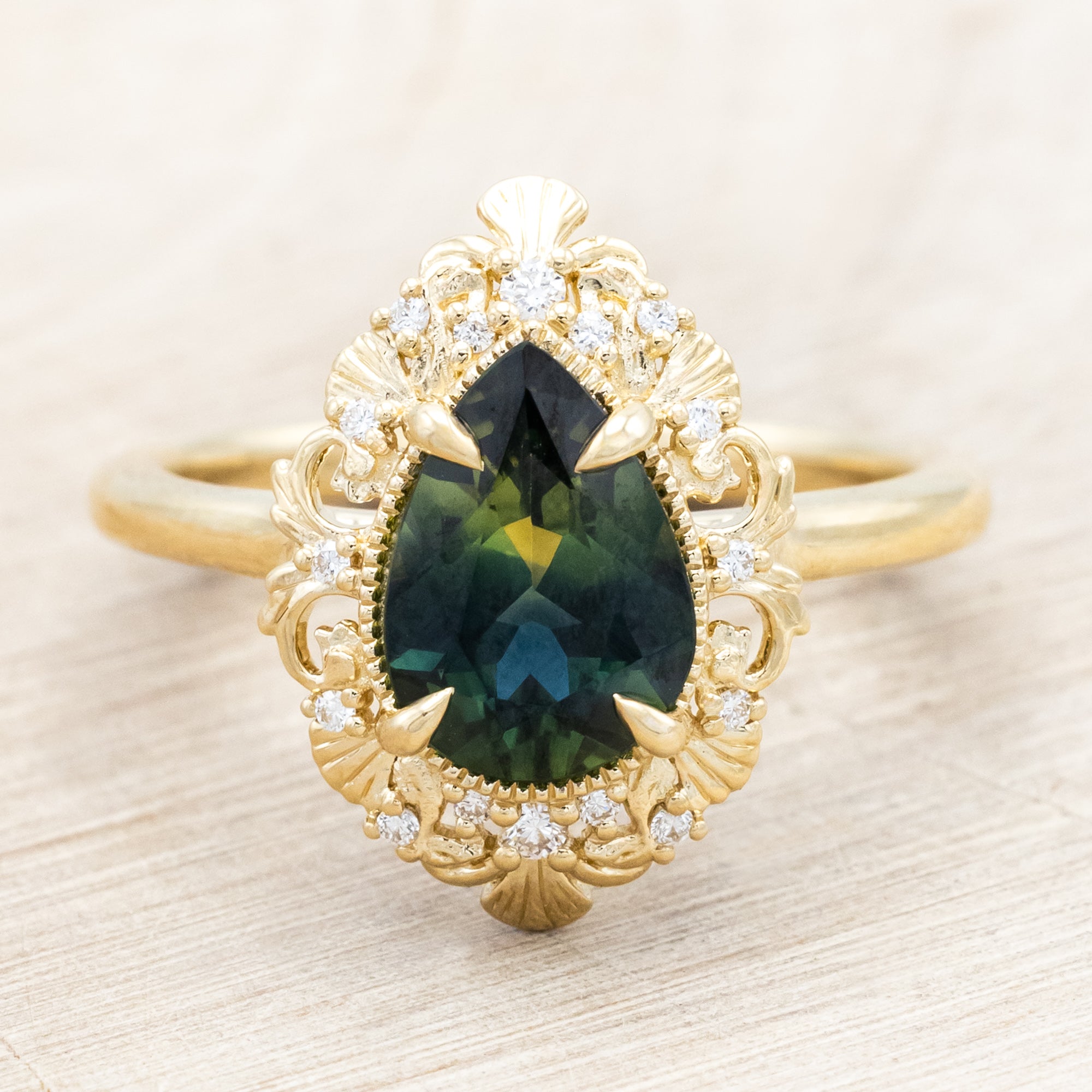 Gold ring with a green sapphire on a light wooden surface