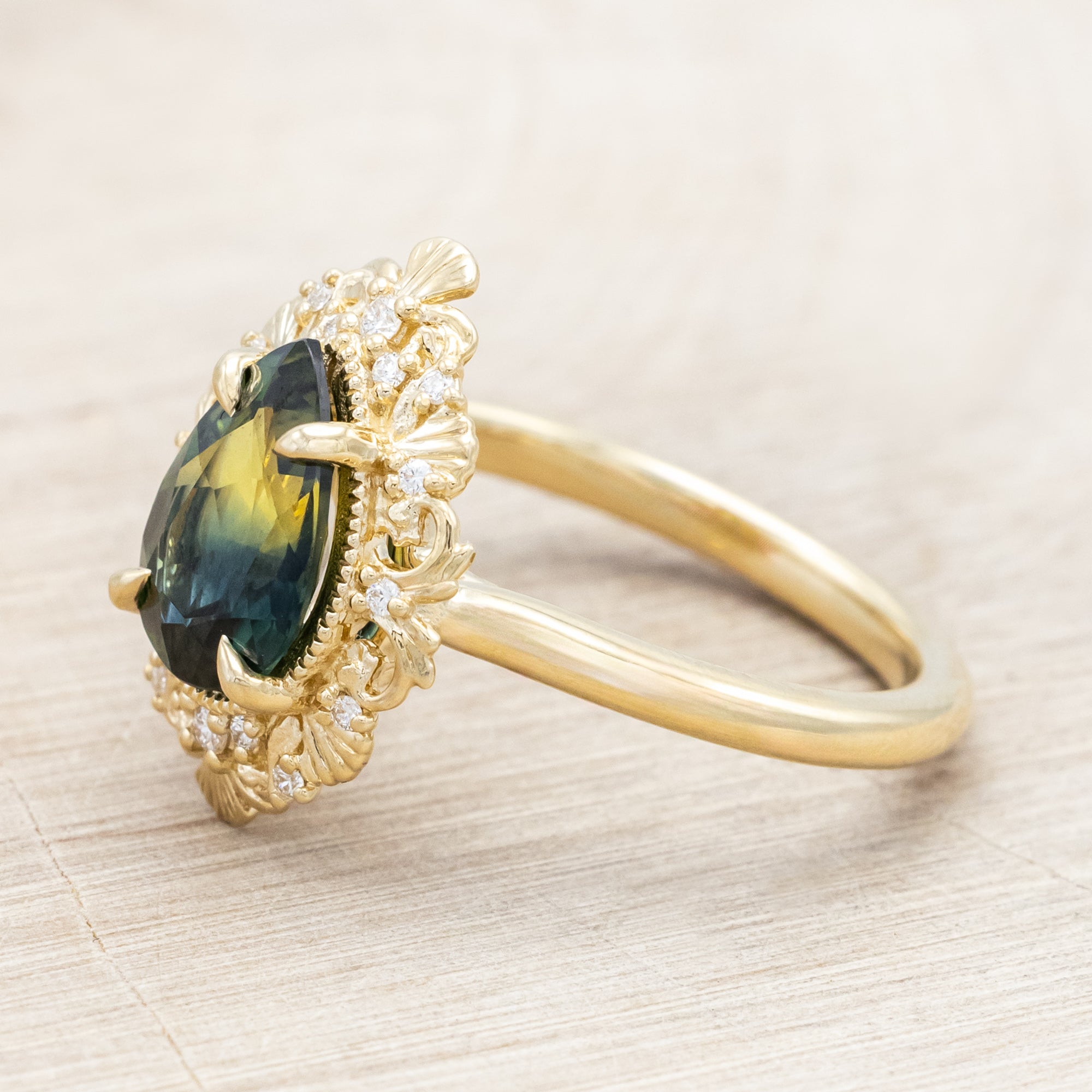 Gold ring with a green sapphire on a light wooden surface