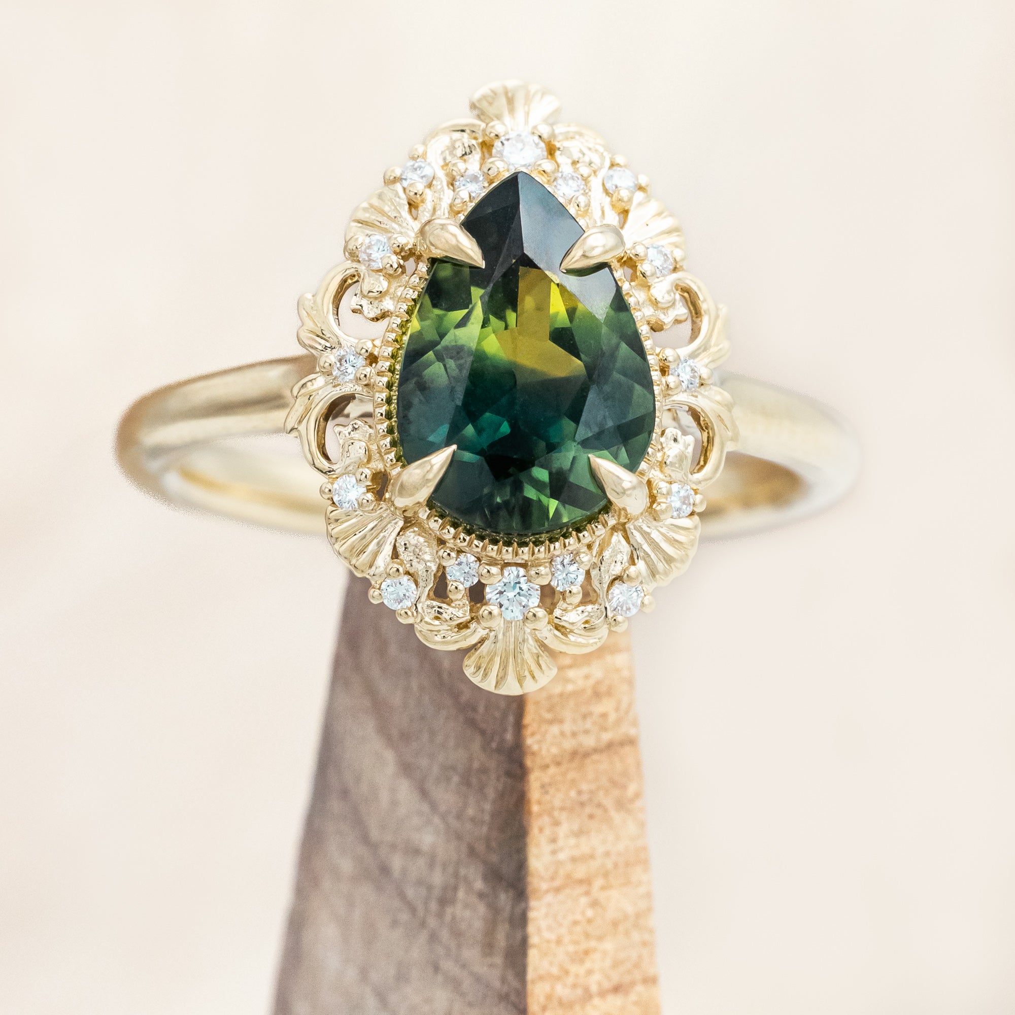 Gold ring with a green sapphire on a beige background