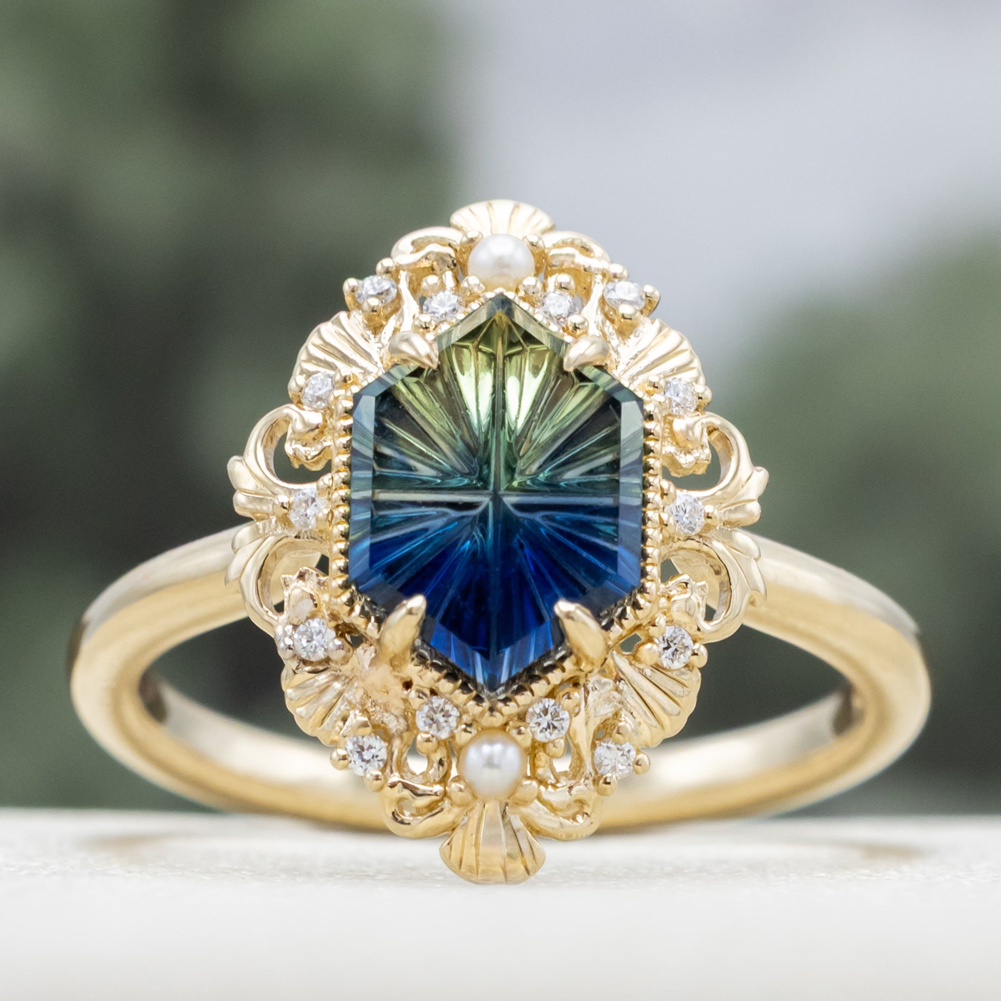 Sculptural gold ring with a blue sapphire on a blurred background