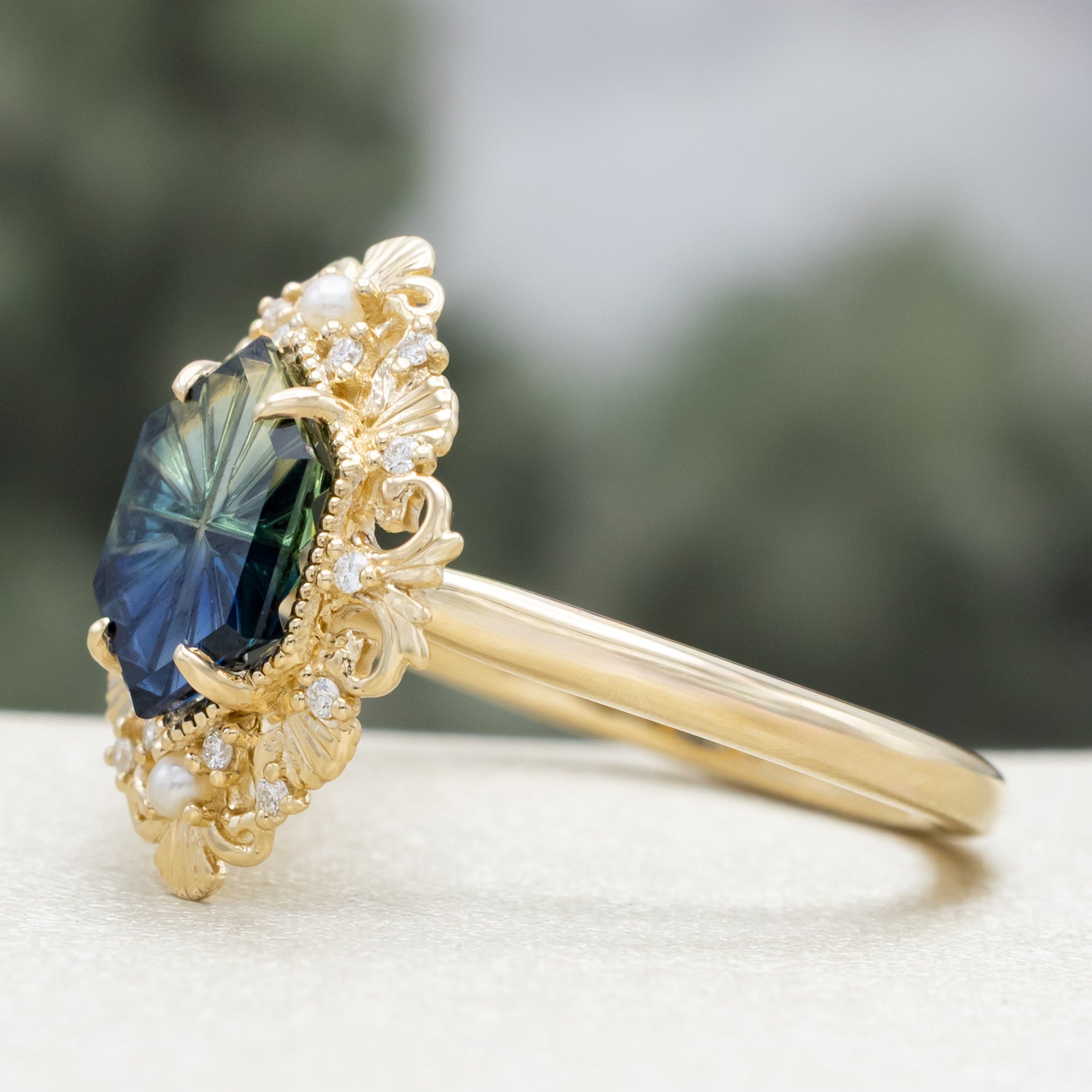 Sculptural gold ring with a blue sapphire on a blurred background