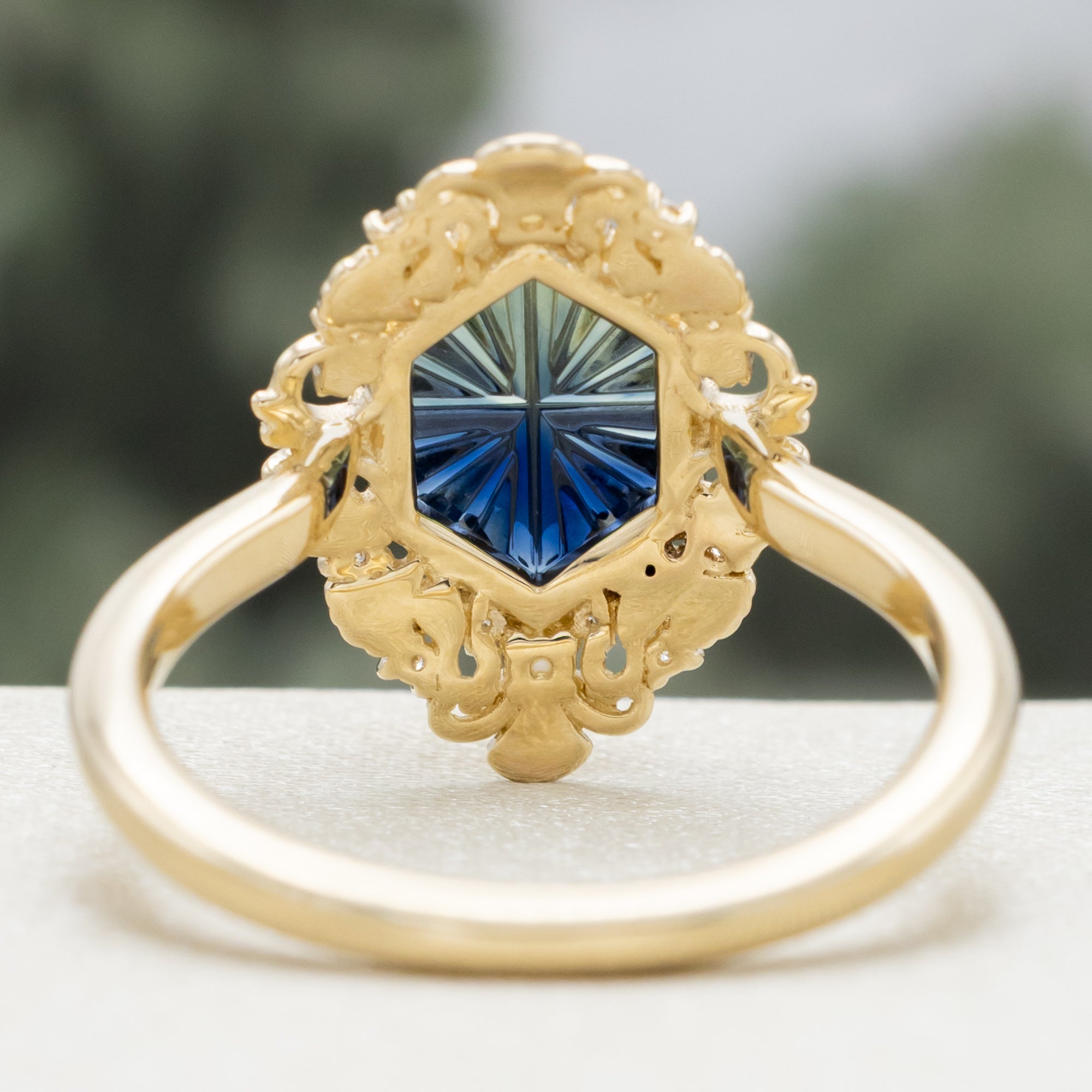 Sculptural gold ring with a blue sapphire on a blurred background
