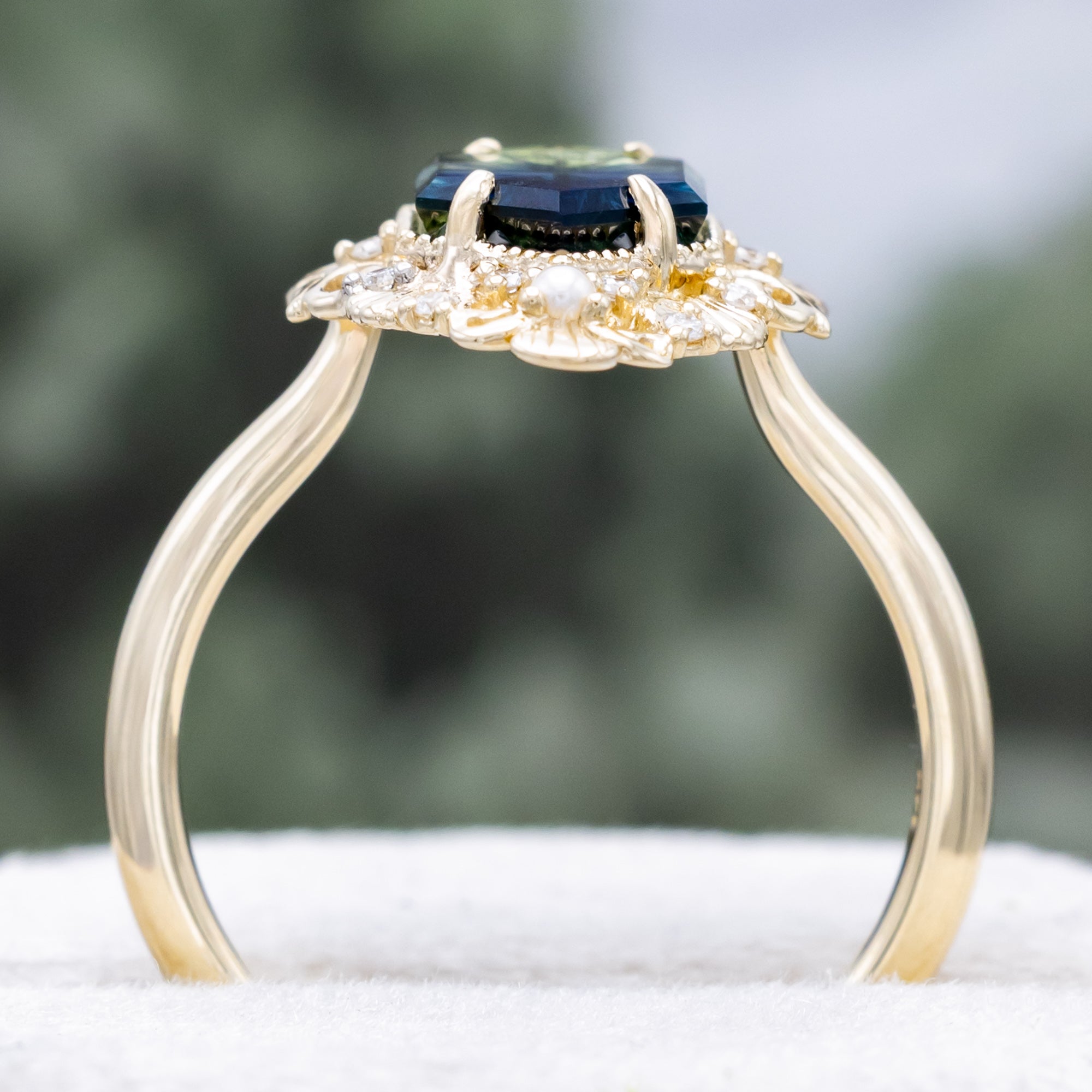 Sculptural gold ring with a blue sapphire on a blurred background