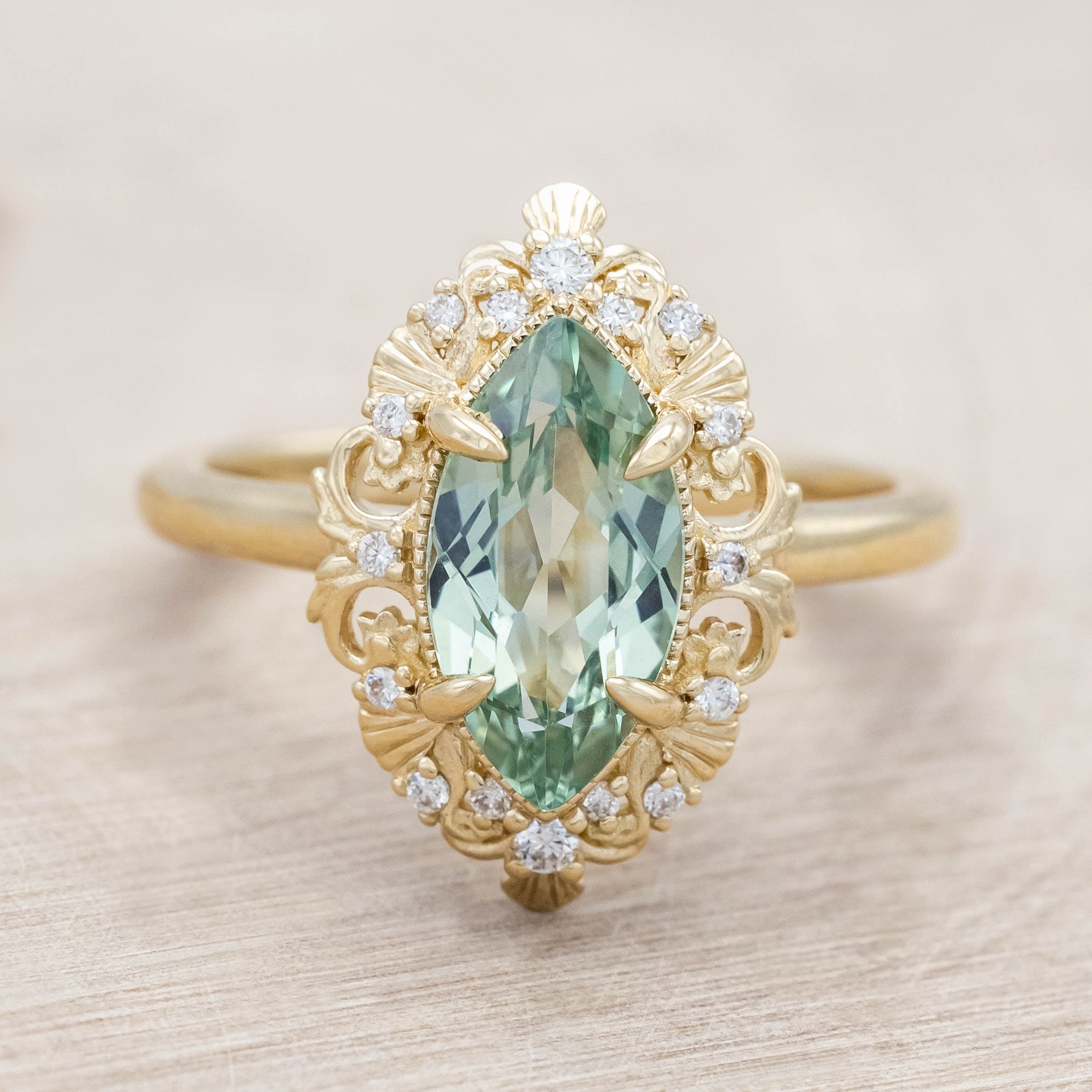 14K gold ring with a green sapphire on a light wooden background