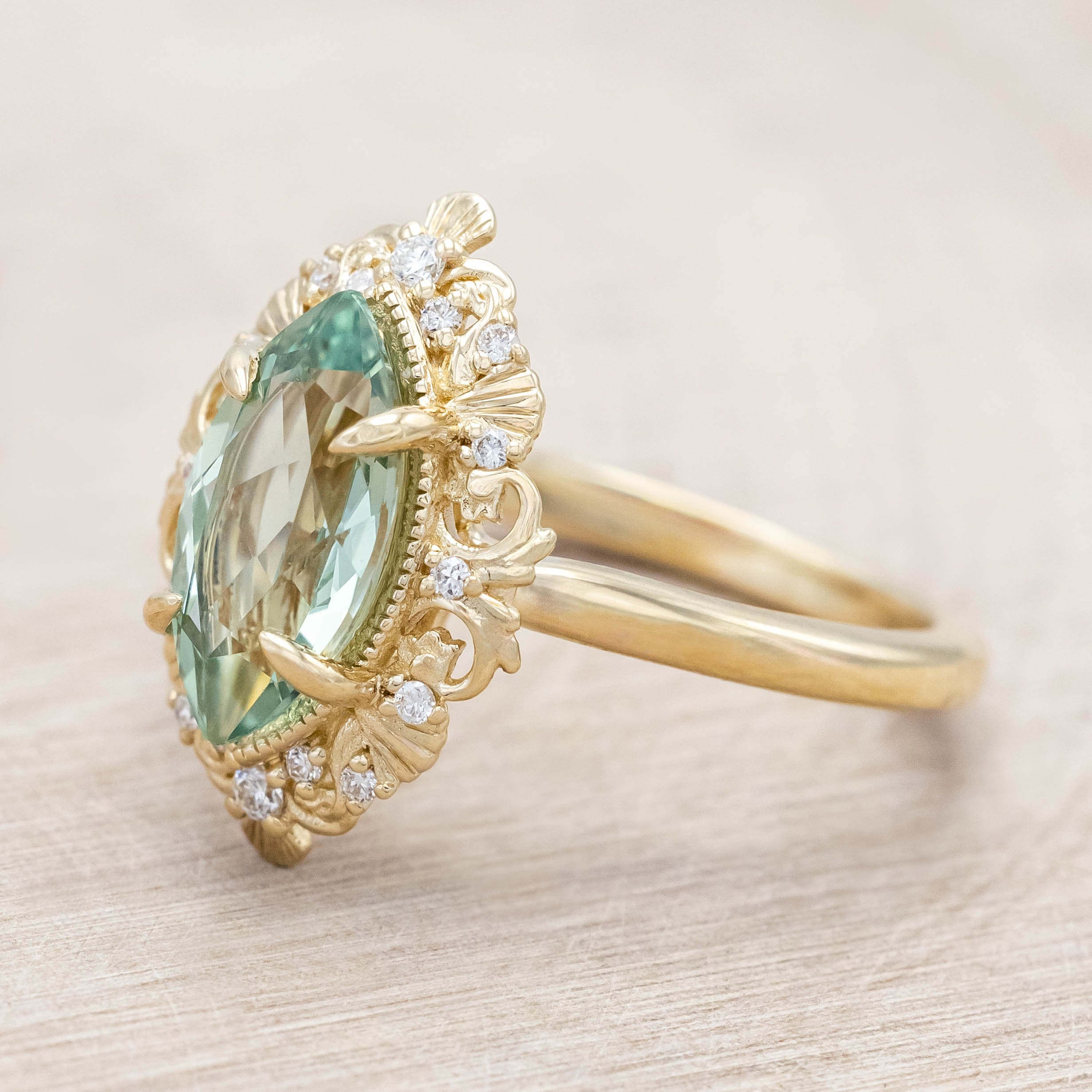 14K gold ring with a green sapphire on a light wooden background
