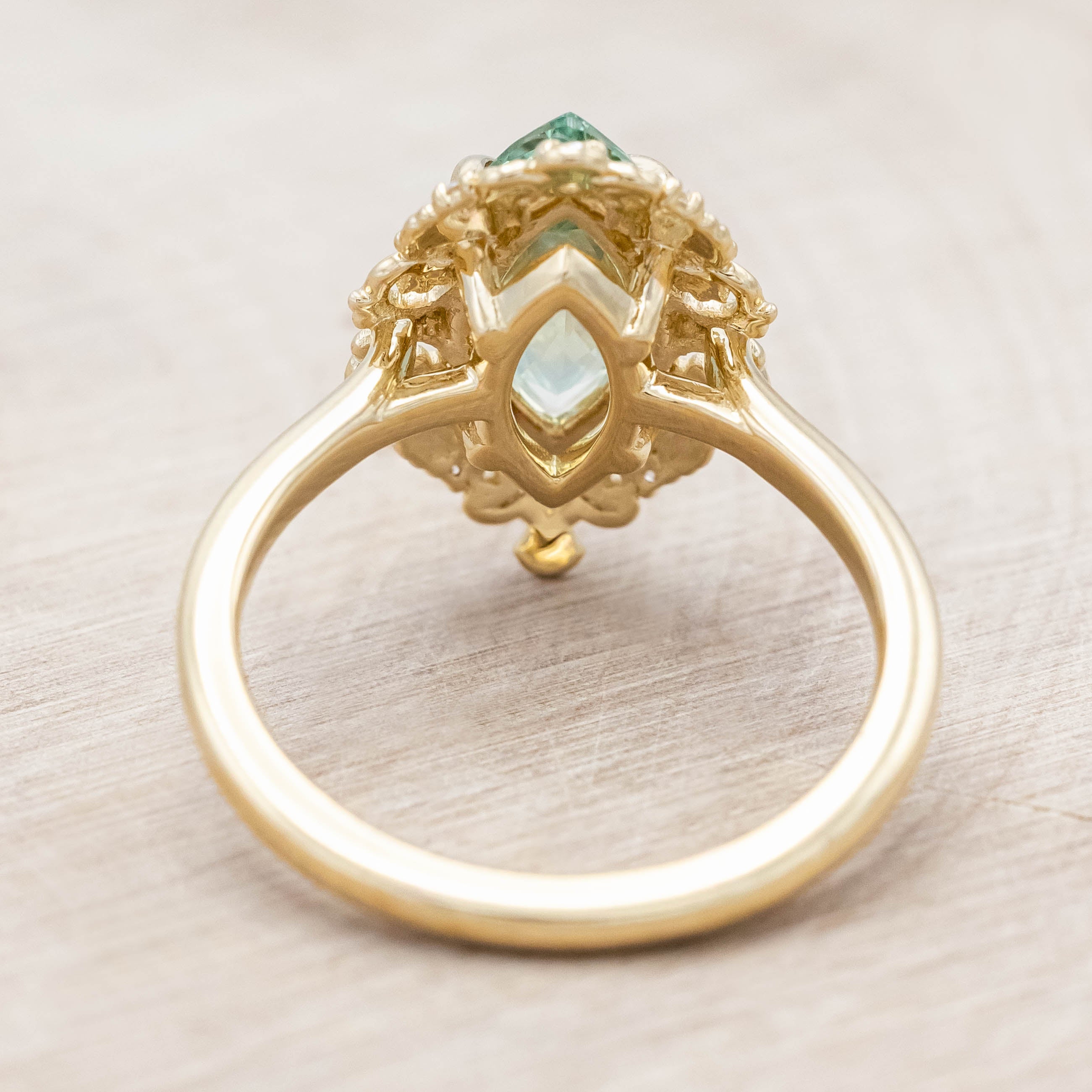 14K gold ring with a green sapphire on a light wooden background
