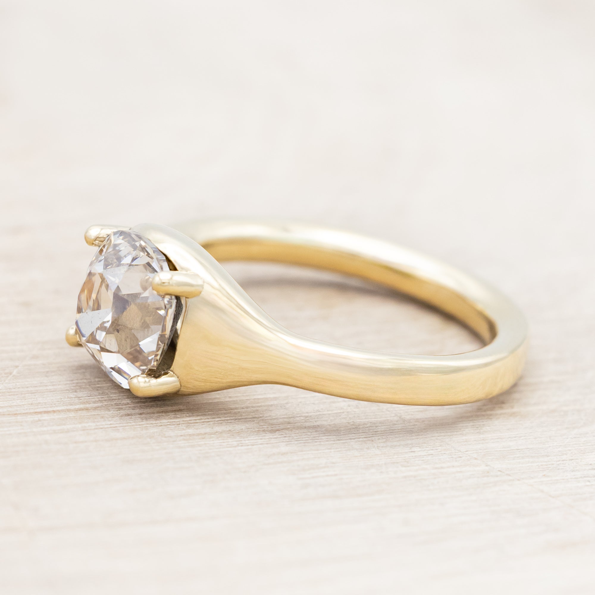 Gold ring with a large salt & pepper diamond on a light wooden surface