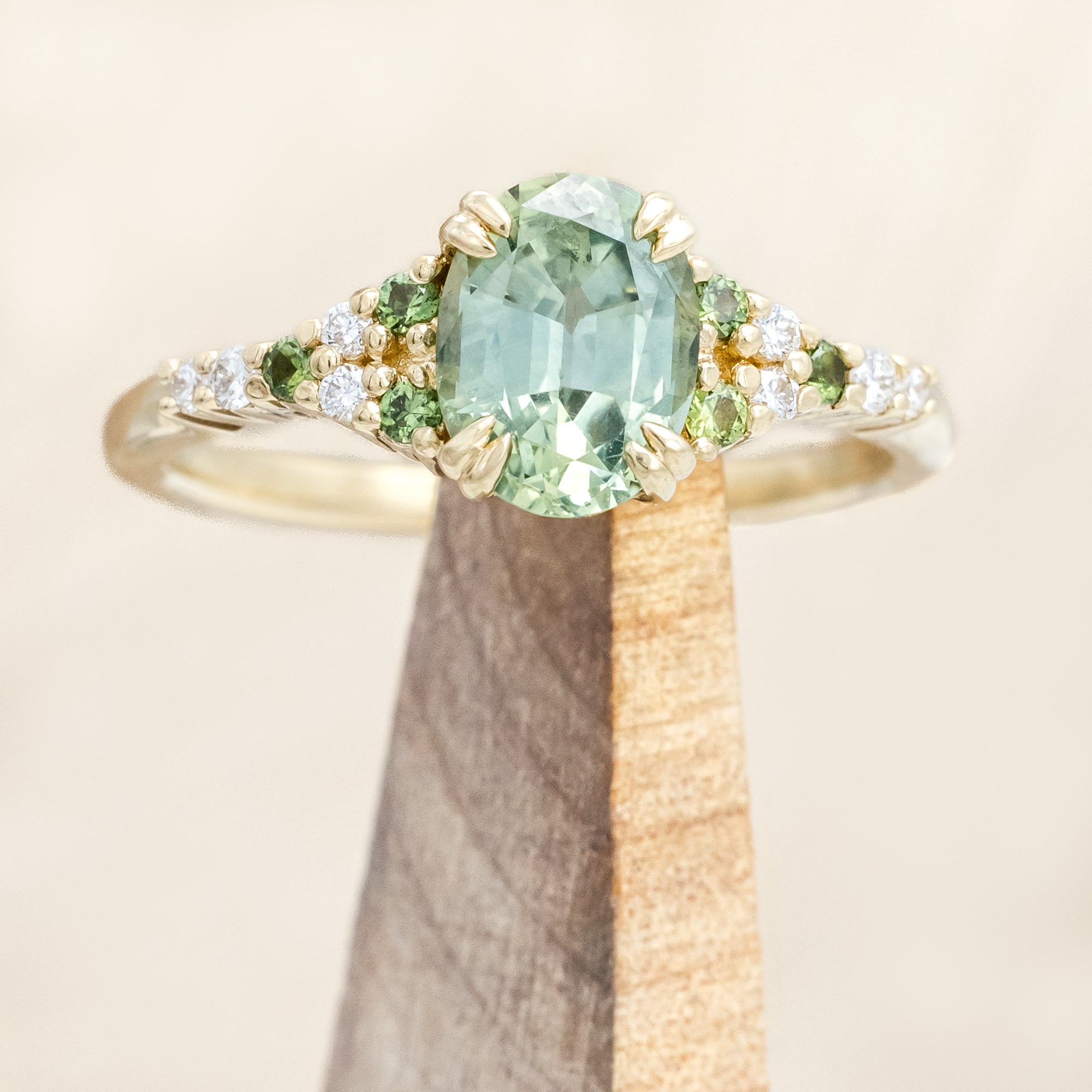 Gold ring with green sapphire and diamond accents on a light wooden surface