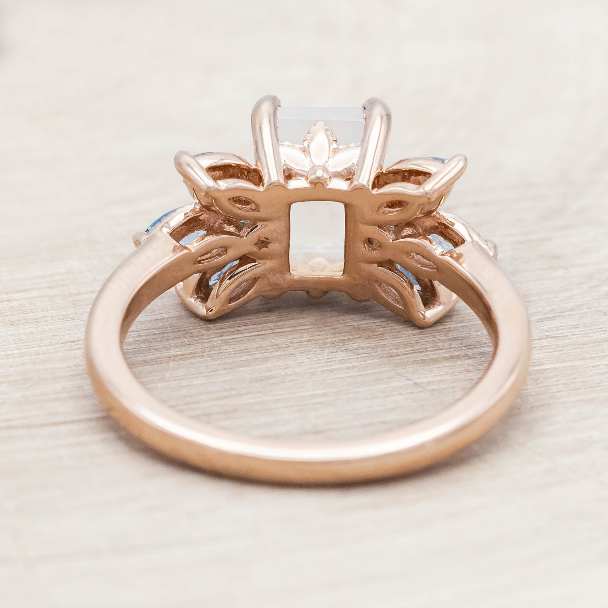 Rose gold ring with a central moonstone surrounded by smaller stones on a neutral background