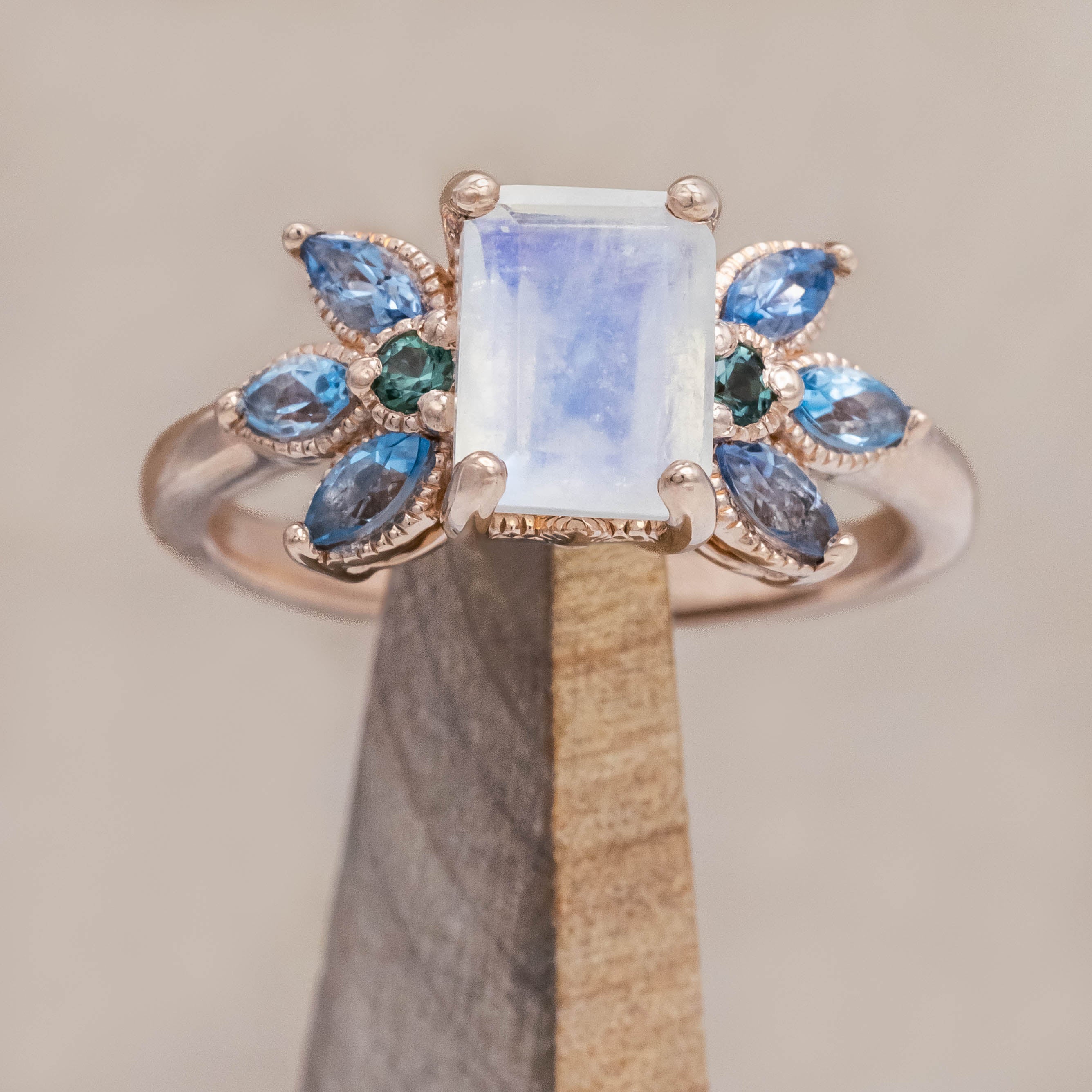 Rose gold ring with a central moonstone surrounded by smaller stones on a neutral background