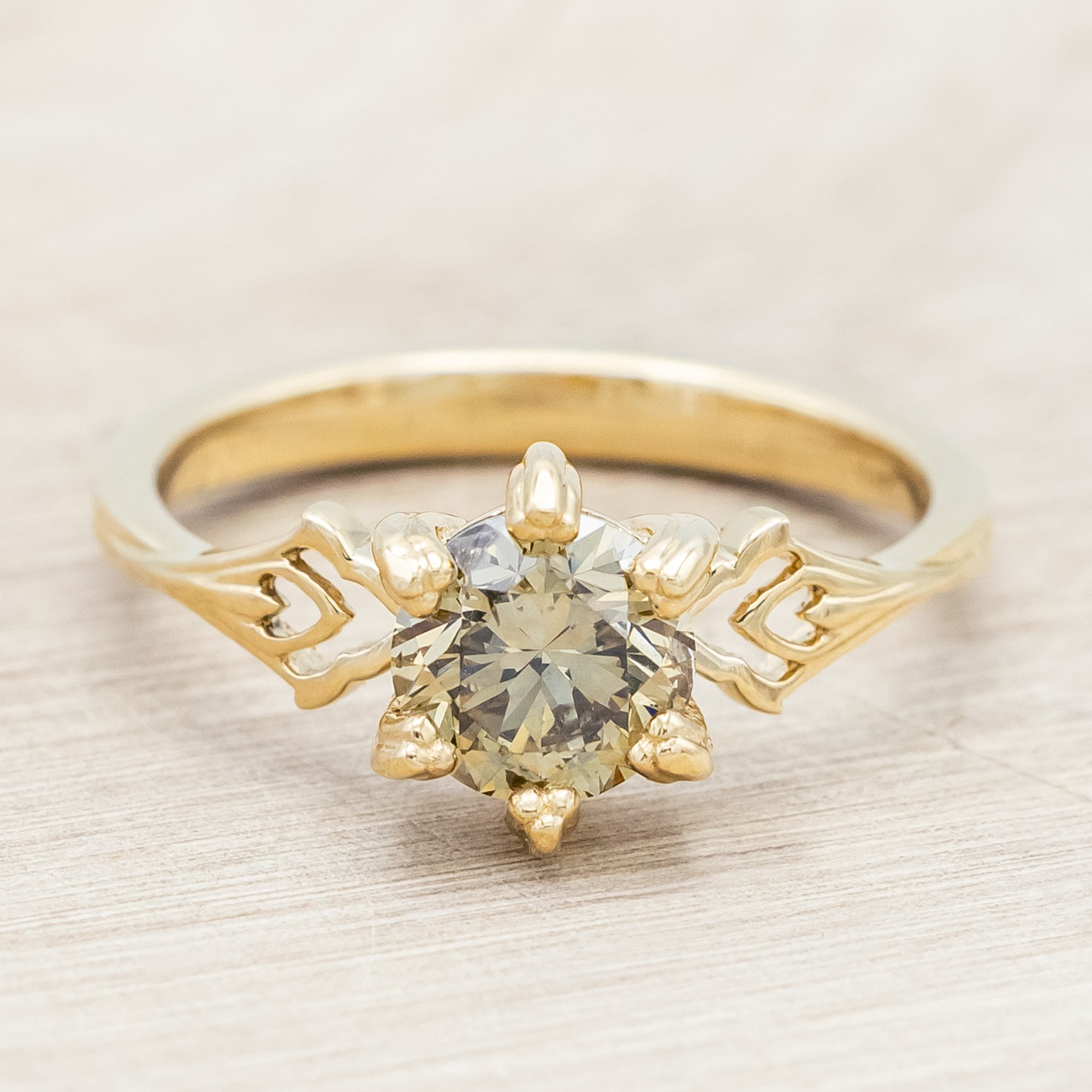 Gold ring with a champagne salt & pepper diamond on against a light wooden surface