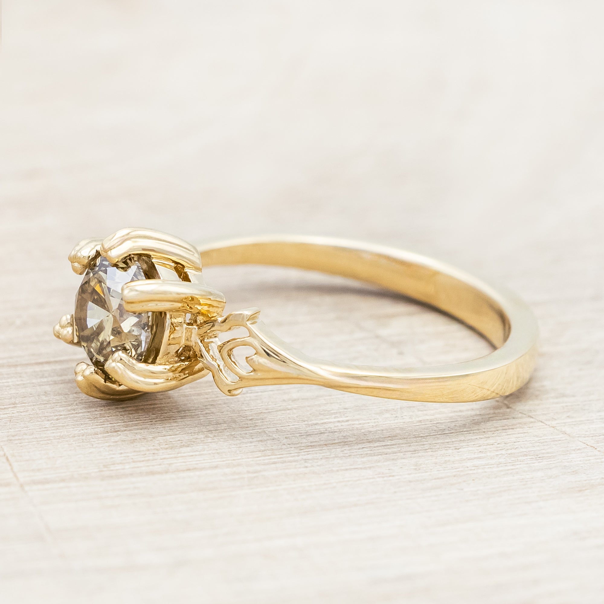 Gold ring with a champagne salt & pepper diamond on against a light wooden surface