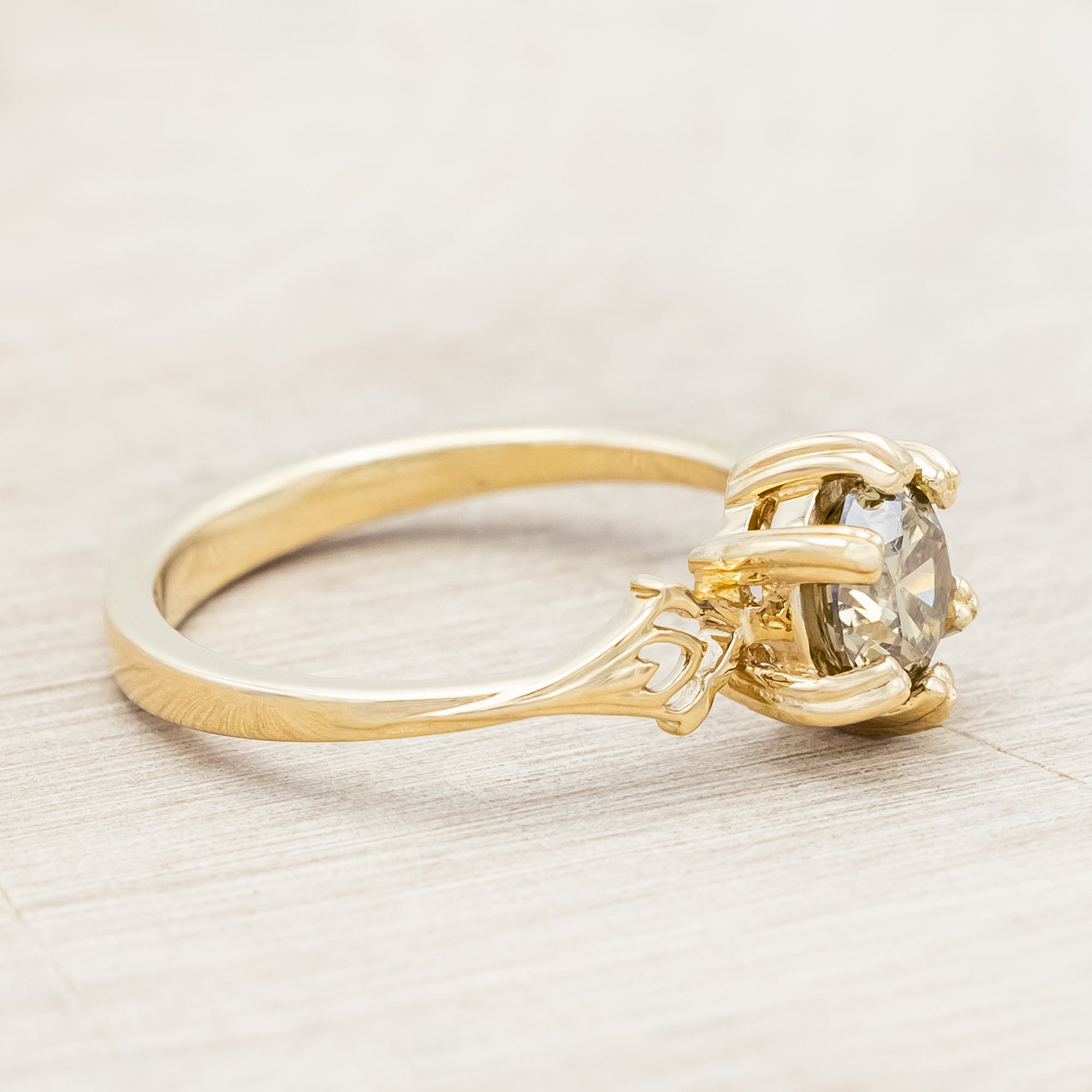 Gold ring with a champagne salt & pepper diamond on against a light wooden surface