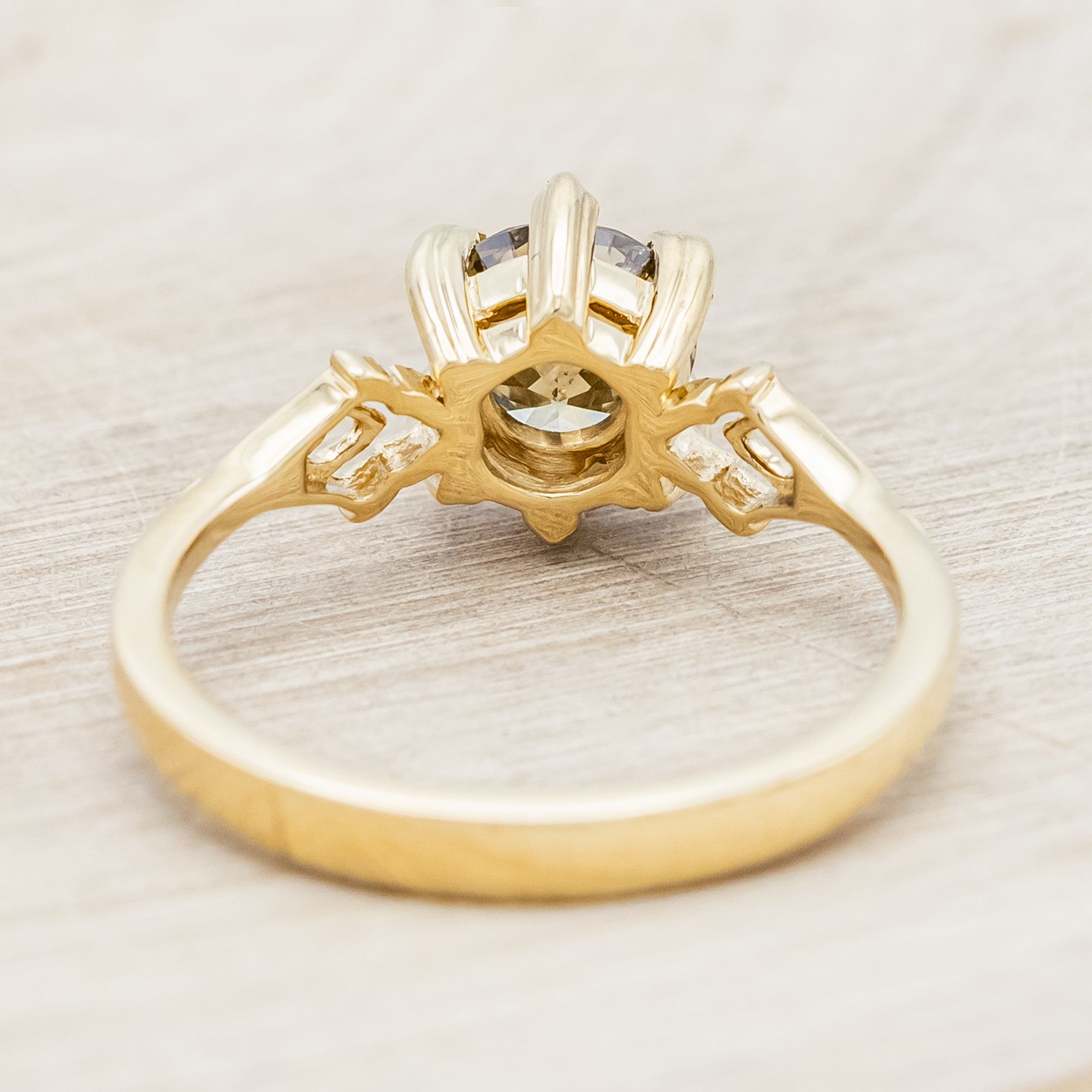 Gold ring with a champagne salt & pepper diamond against a light wooden surface