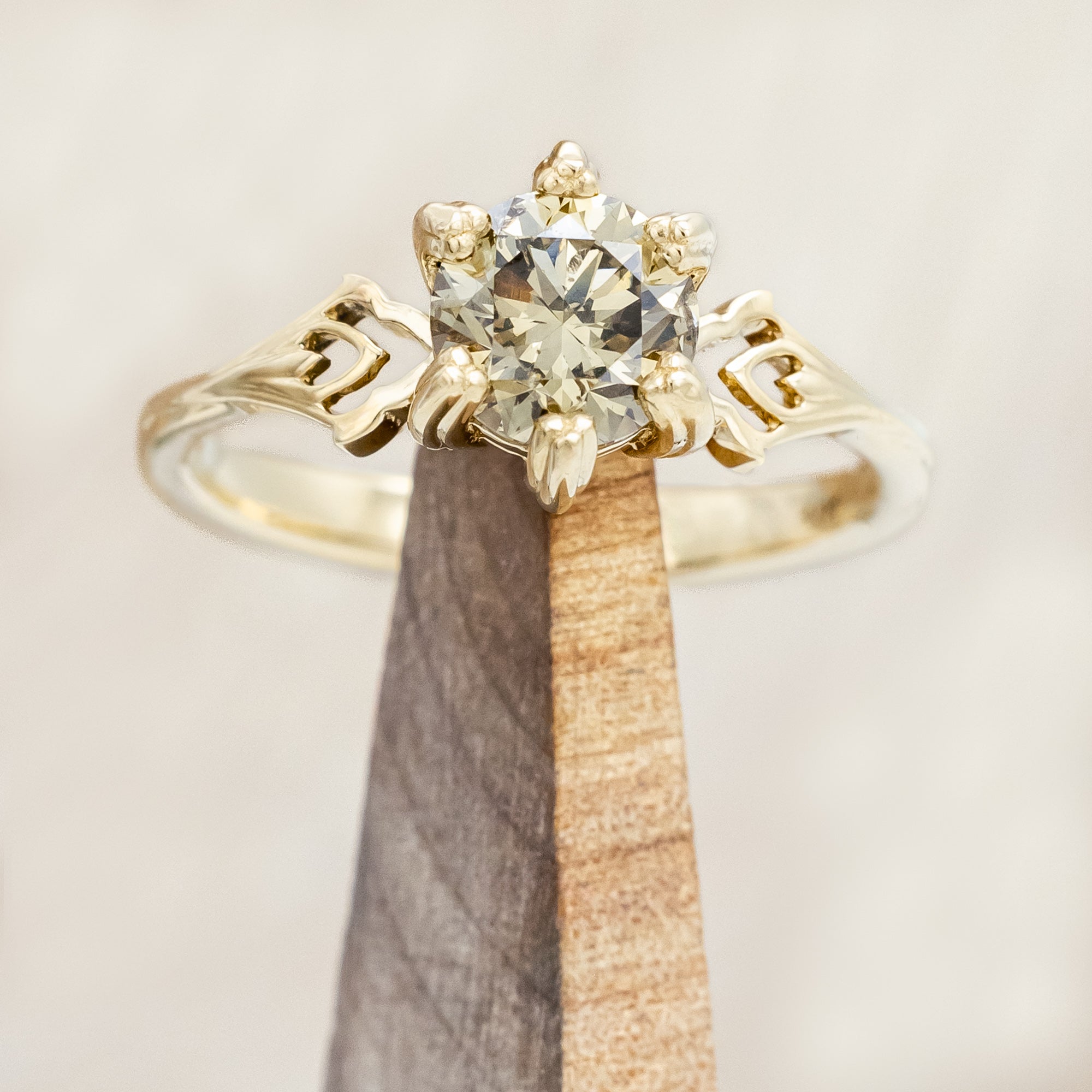Gold ring with a champagne salt & pepper diamond on a wooden stand against a light background