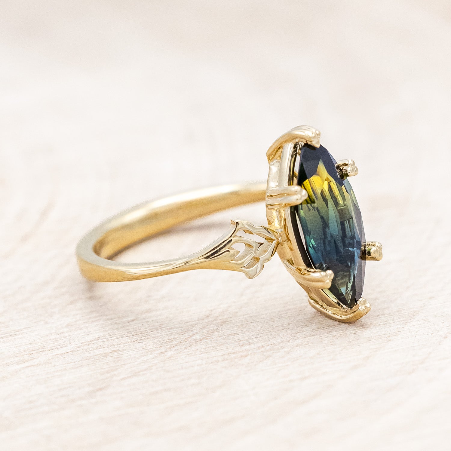 Side view of "Morrigan" - solitaire Australian sapphire women's engagement ring on an ornate 14K yellow gold band