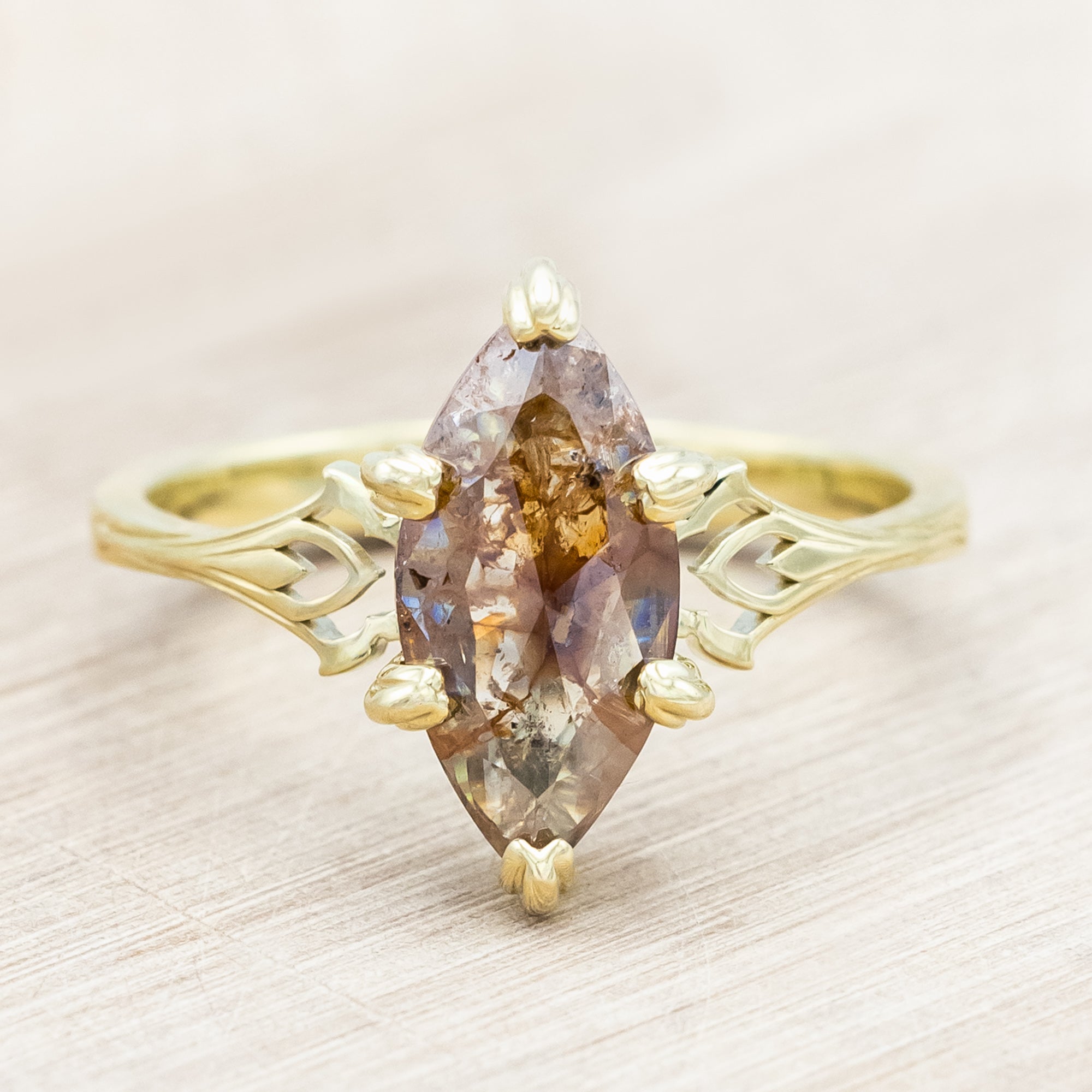 Gold ring with a marquise cut salt & pepper diamond on a light wooden surface