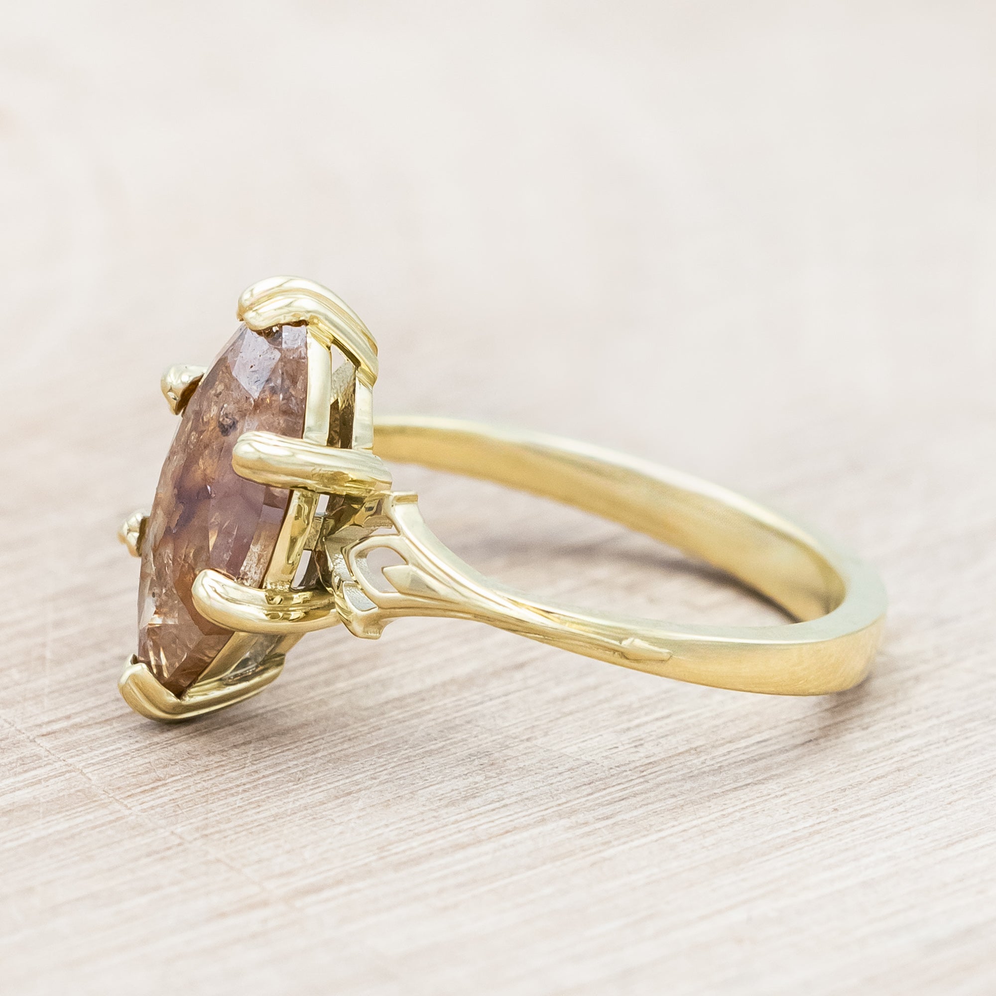 Gold ring with a marquise cut salt & pepper diamond on a light wooden surface