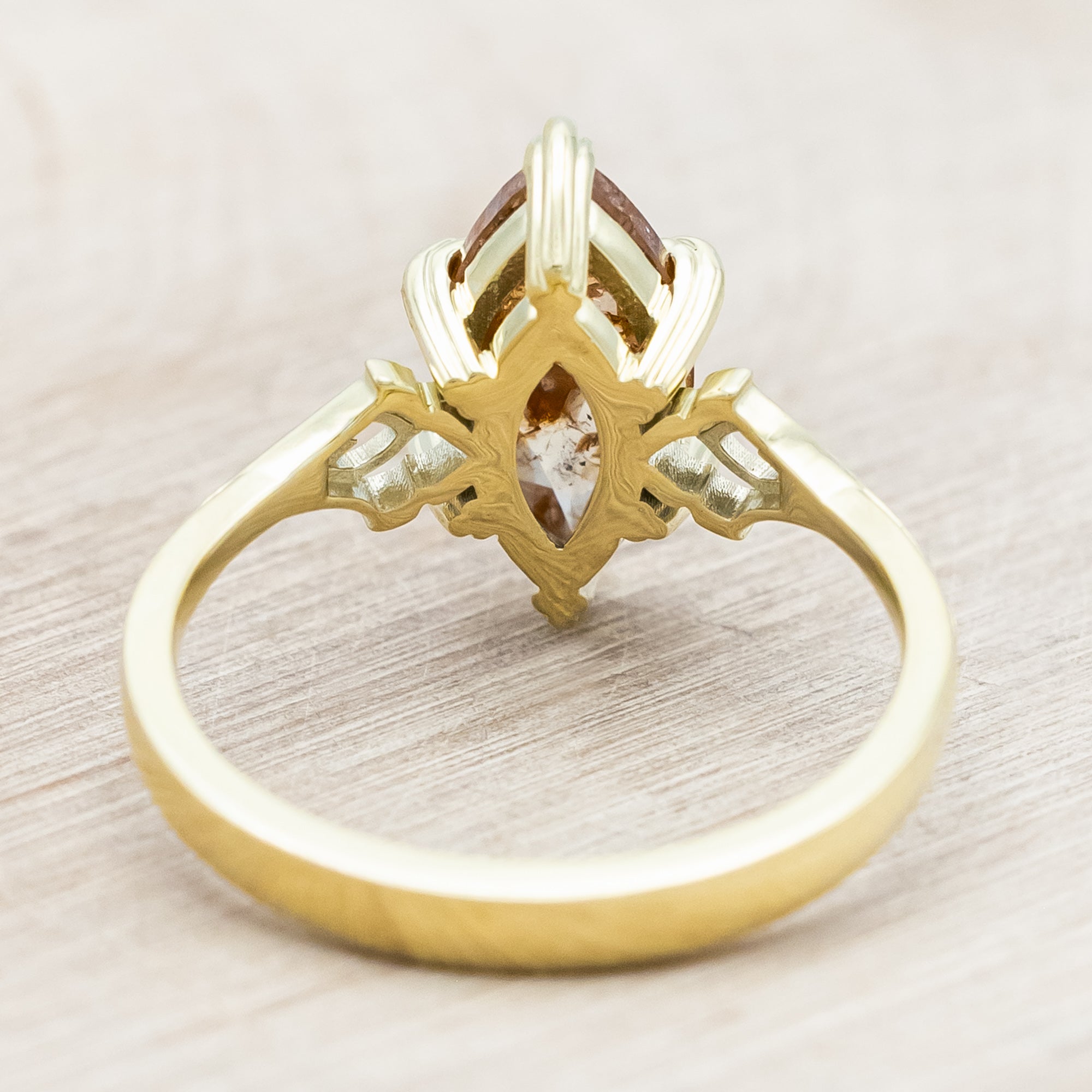 Gold ring with a marquise cut salt & pepper diamond on a light wooden surface