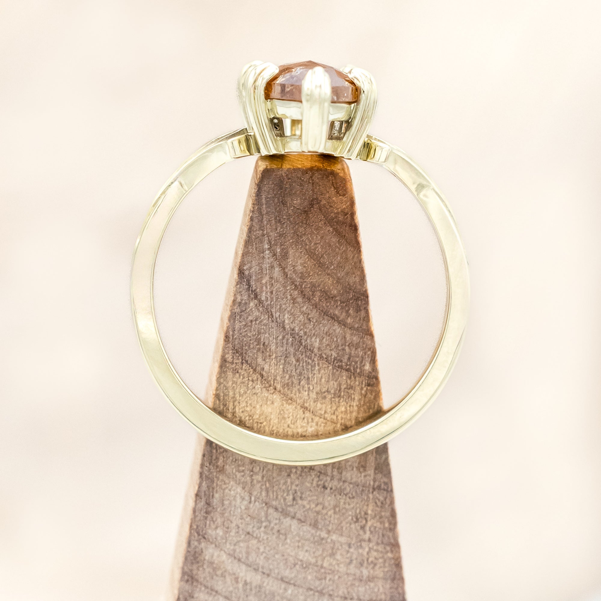 Gold ring with a marquise cut salt & pepper diamond on a wooden stand against a light background
