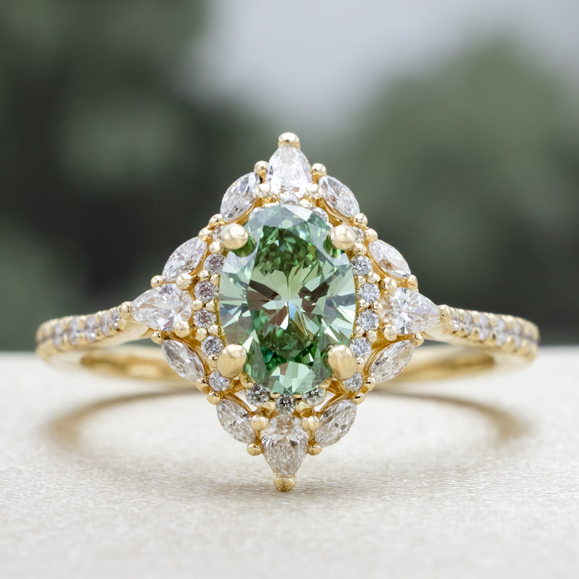 Gold ring with a green lab diamond and diamond accents on a neutral background