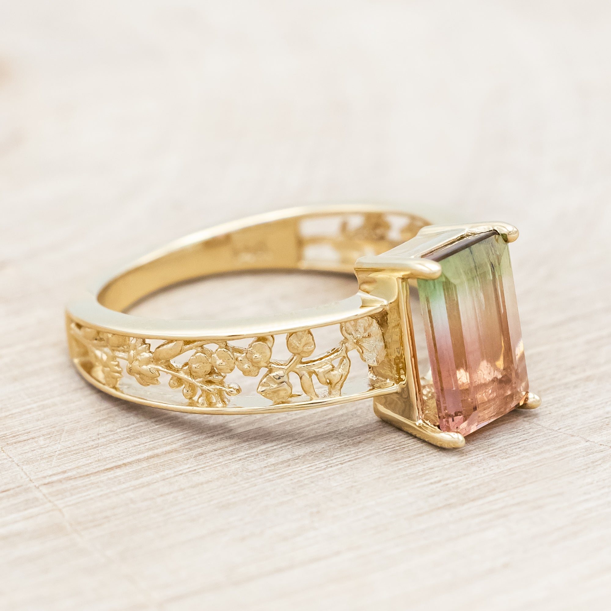 14K gold ring with a green and pink gemstone on a beige background