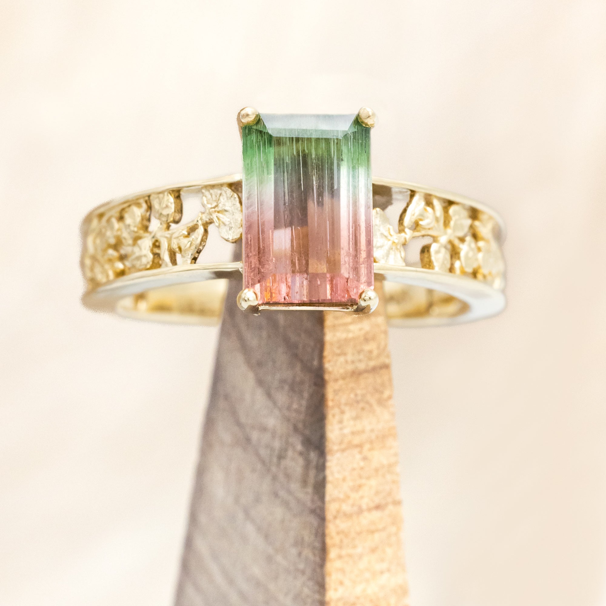 14K gold ring with a green and pink gemstone on a beige background