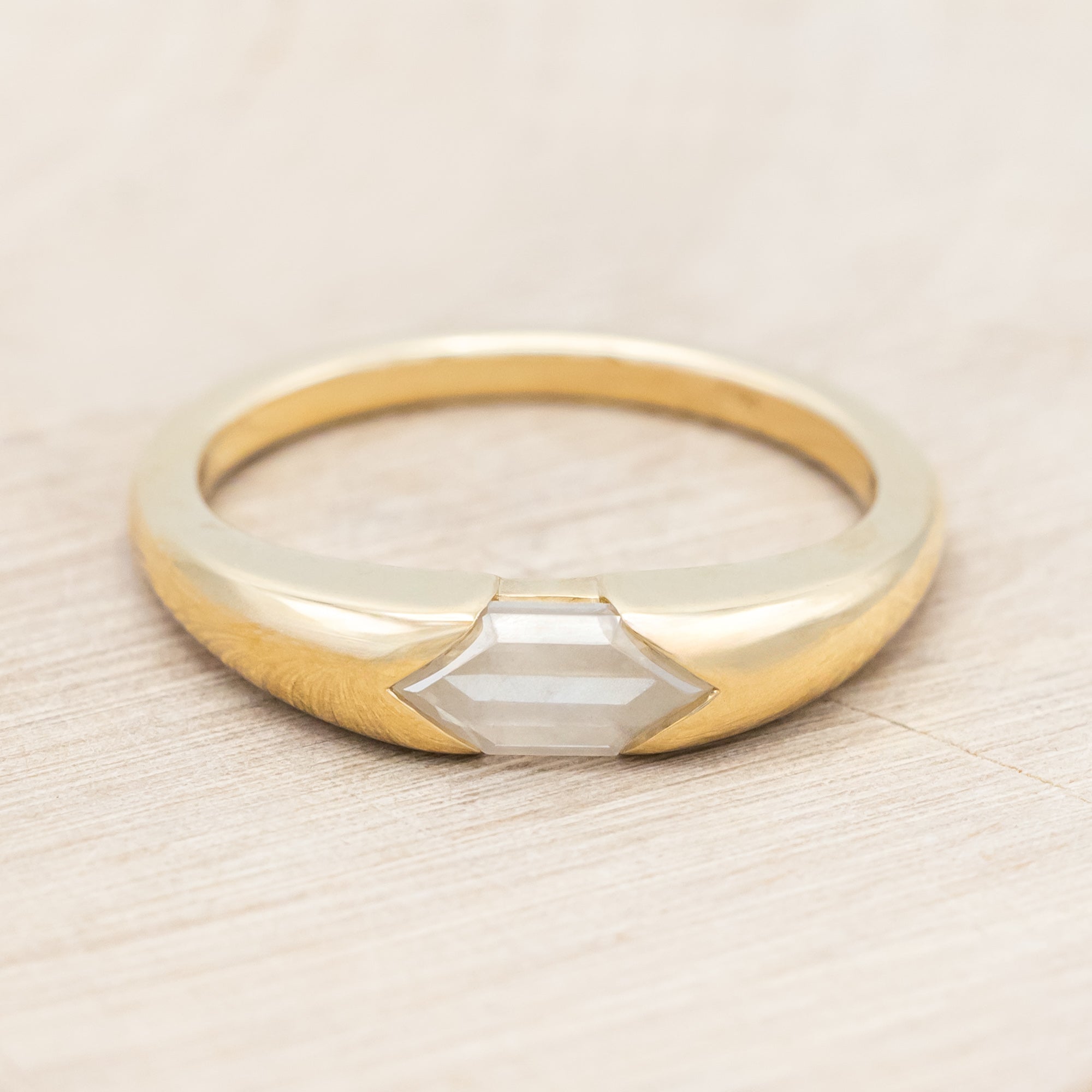 14K gold ring with a geometric stone on a wooden background
