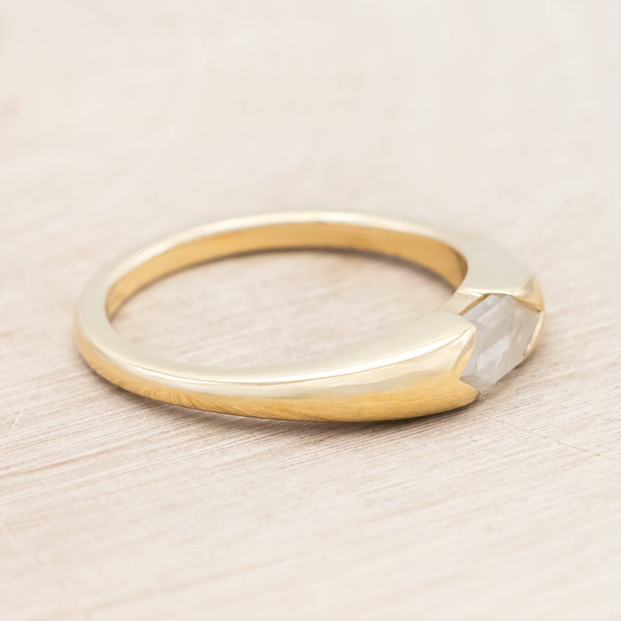 14K gold ring with a geometric stone on a wooden background