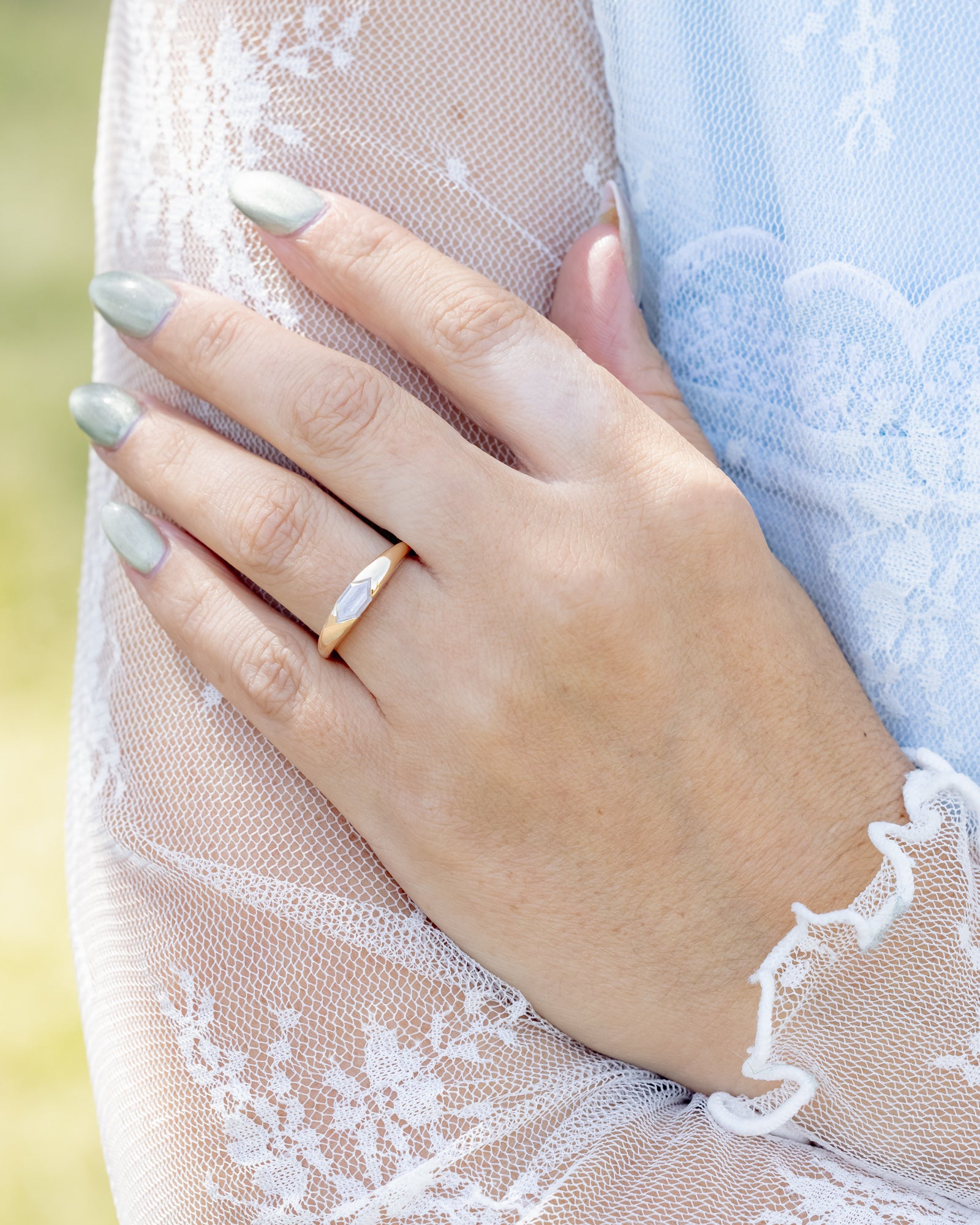 Hand wearing a gold ring with a blurred background