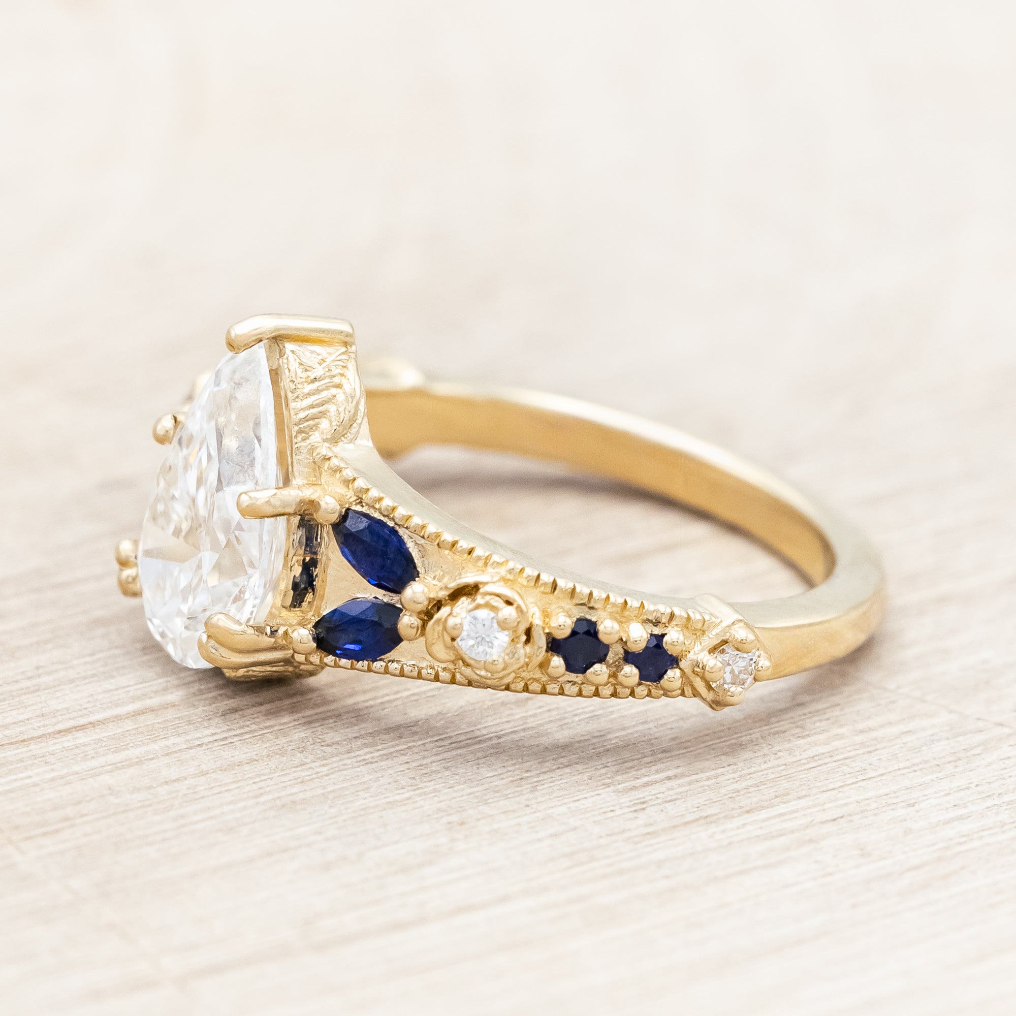 14K yellow gold ring with lab diamond and blue sapphires on a beige background