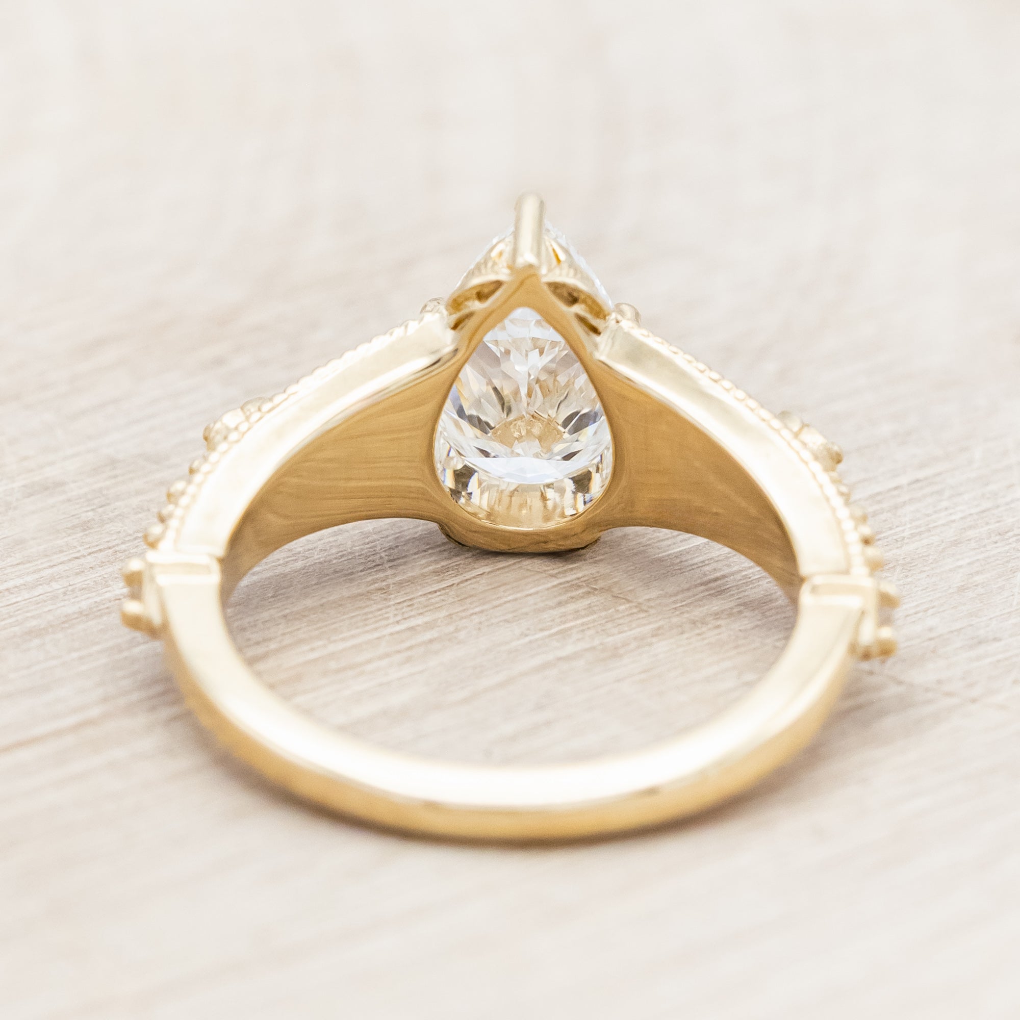 14K yellow gold ring with lab diamond and blue sapphires on a beige background