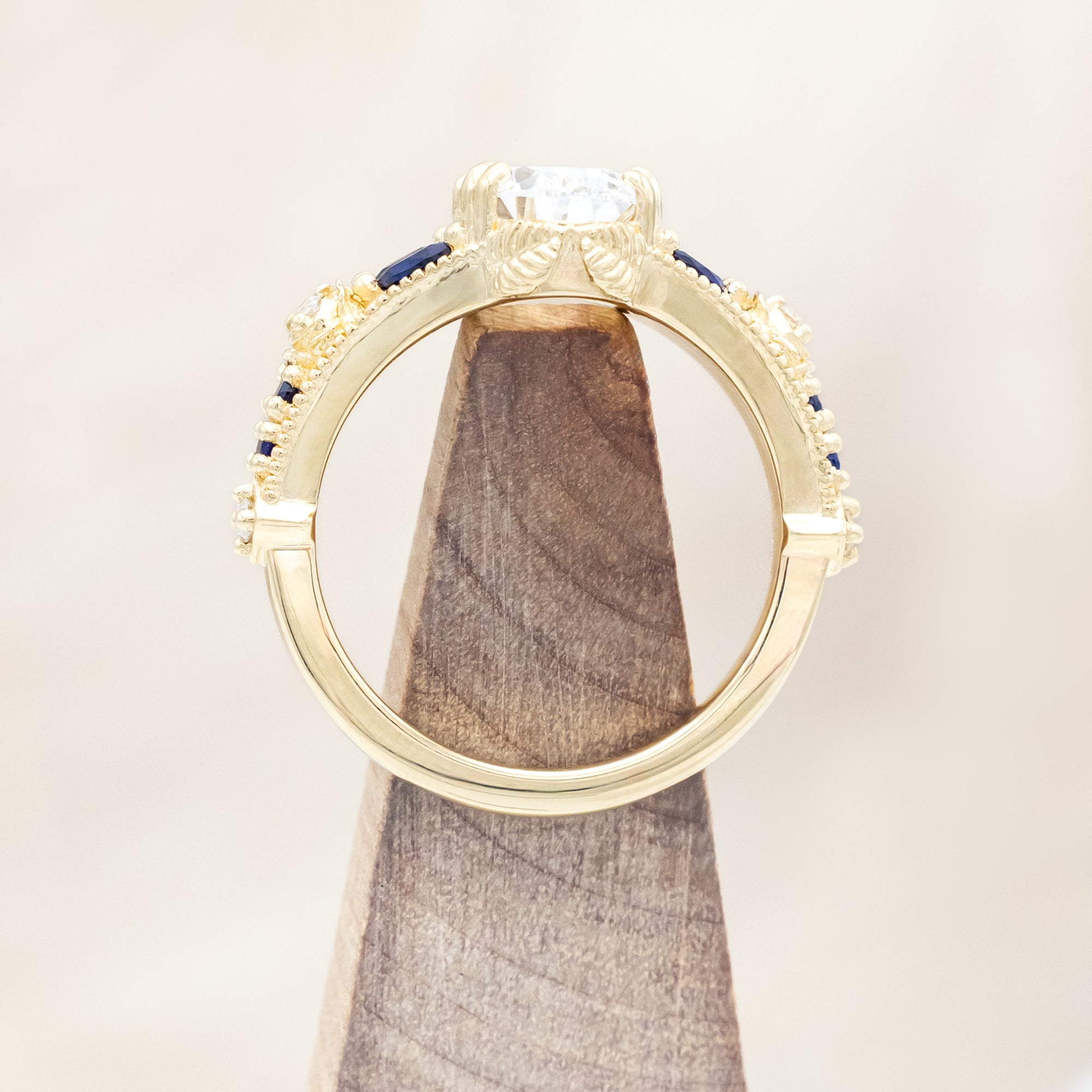 14K yellow gold ring with lab diamond and blue sapphires on a beige background