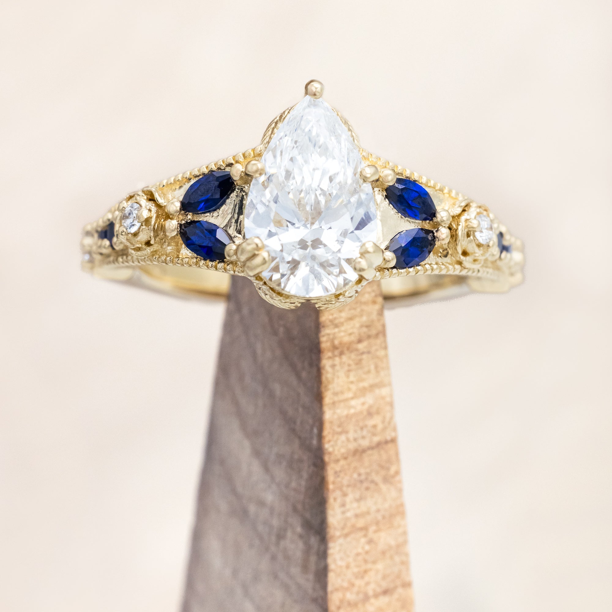 14K yellow gold ring with lab diamond and blue sapphires on a beige background
