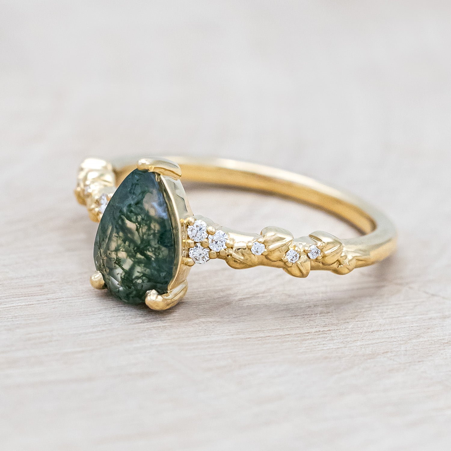 Side view of "Lynette" - pear cut moss agate women's engagement ring with diamond accents on leaf band