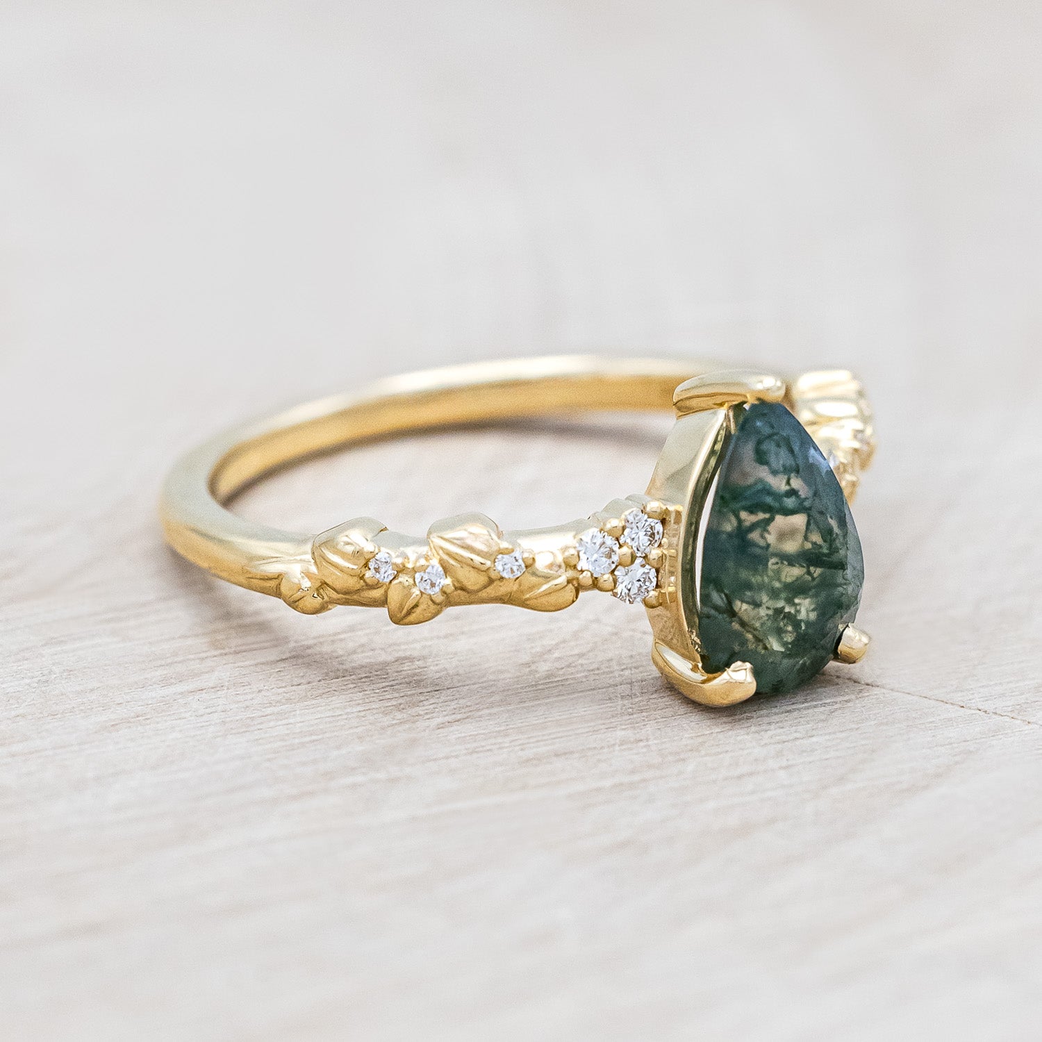 Side view of "Lynette" - pear cut moss agate women's engagement ring with diamond accents on leaf band