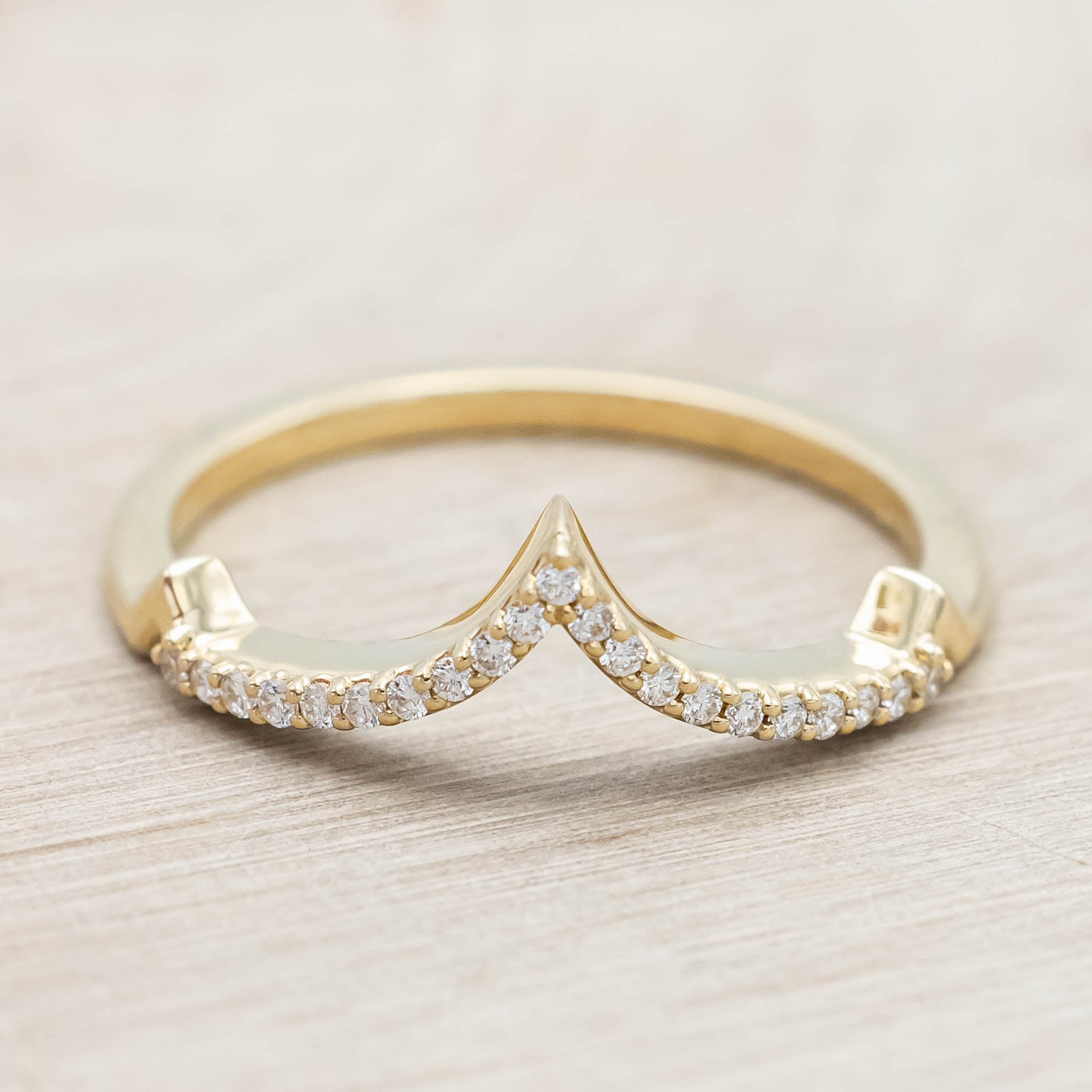 Gold ring with diamonds on a light wooden background