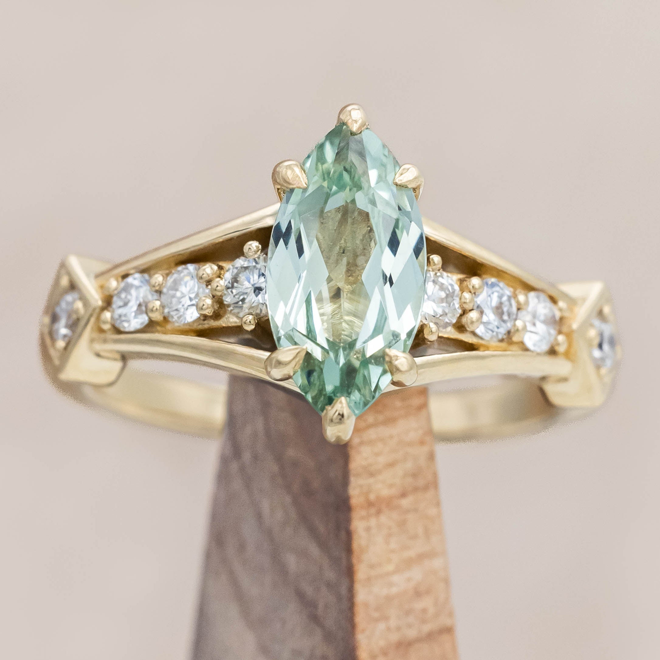 Gold ring with a green sapphire and diamonds on a beige background